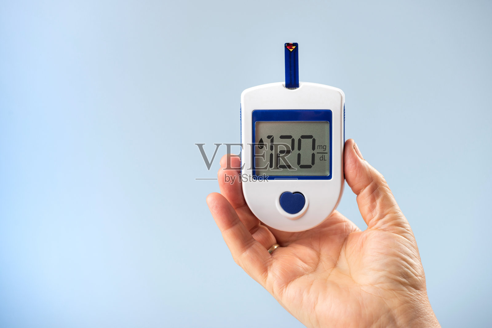 一名妇女手里拿着一个血糖仪，在血糖仪上写下120毫克/分升。照片摄影图片