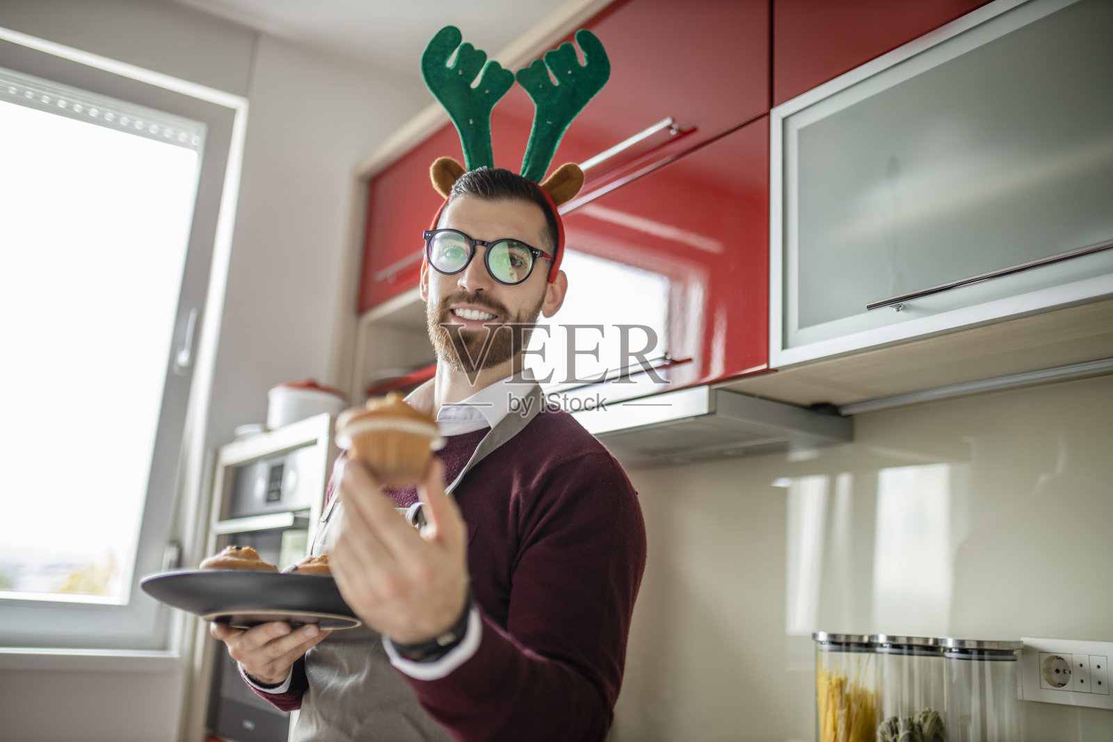 一个年轻人正在家里的厨房里准备圣诞晚餐。他正在准备松饼作甜点照片摄影图片