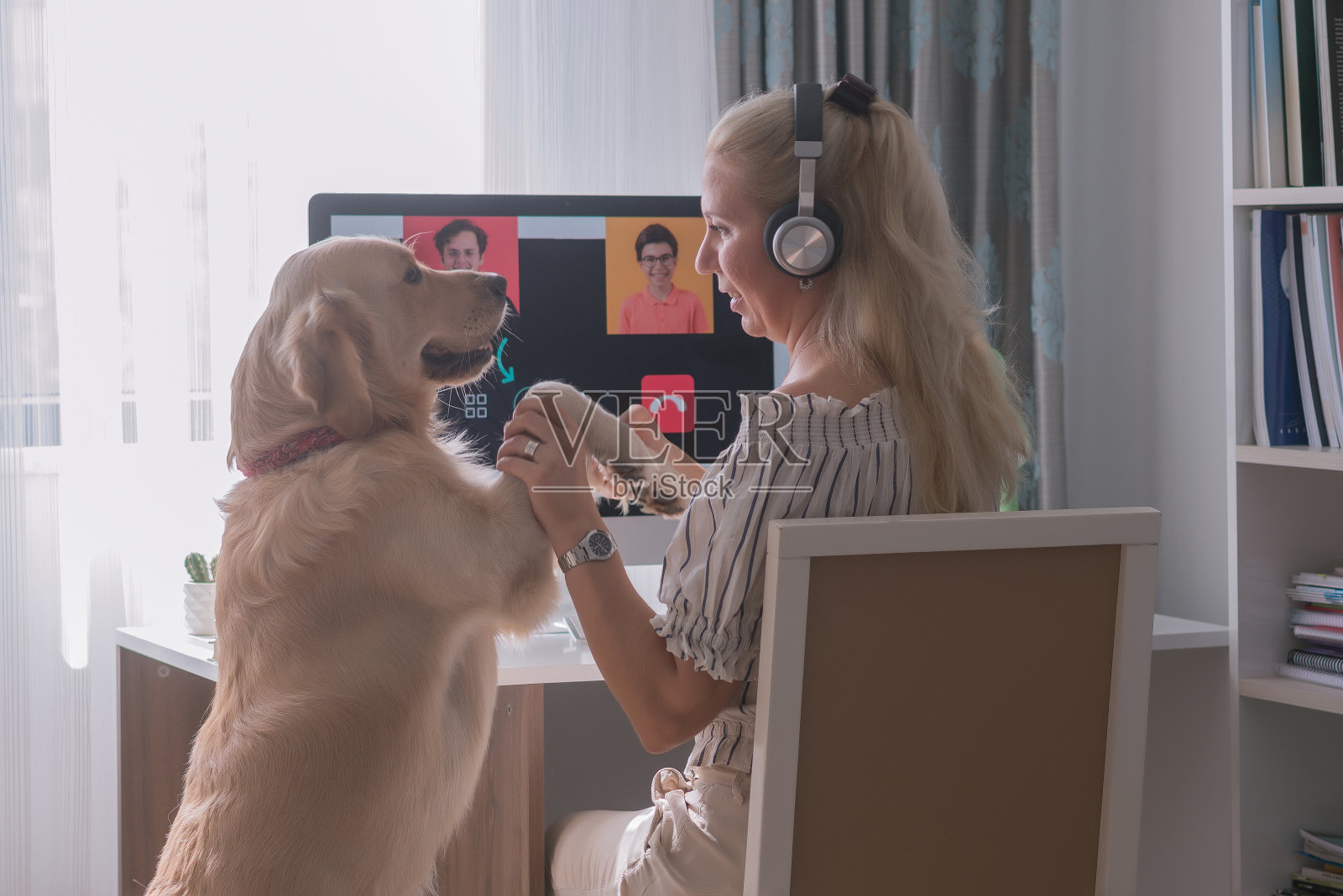 一位妇女和她的家人和狗在电脑前召开电话会议。照片摄影图片