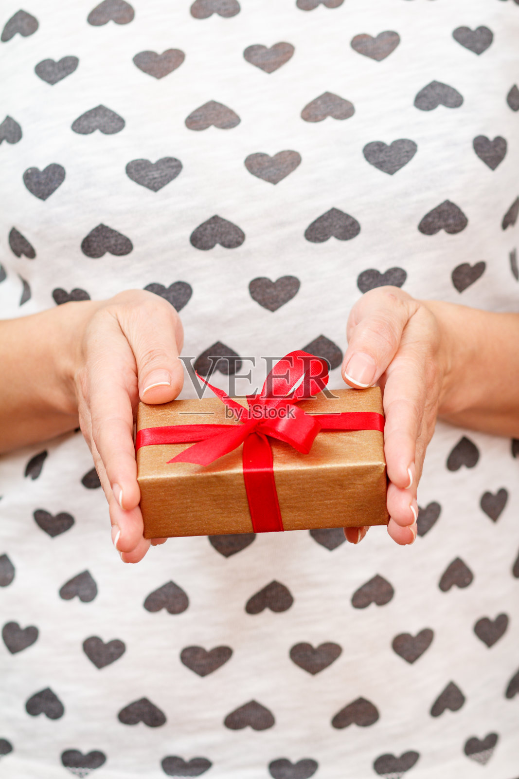 女人手里拿着一个用红丝带系着的礼盒照片摄影图片