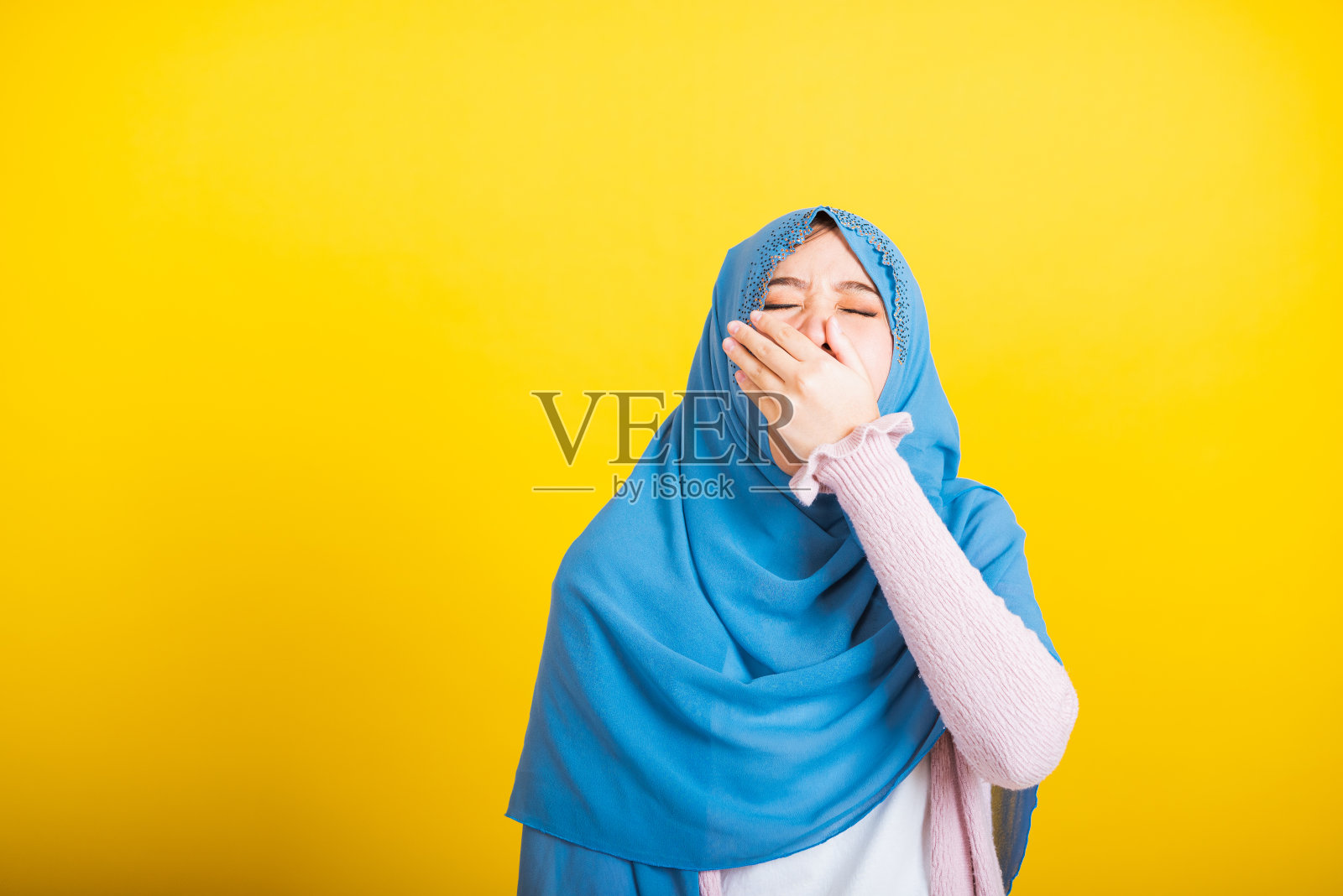 亚洲穆斯林阿拉伯妇女伊斯兰戴着头巾，她昏昏欲睡打哈欠张大了嘴照片摄影图片