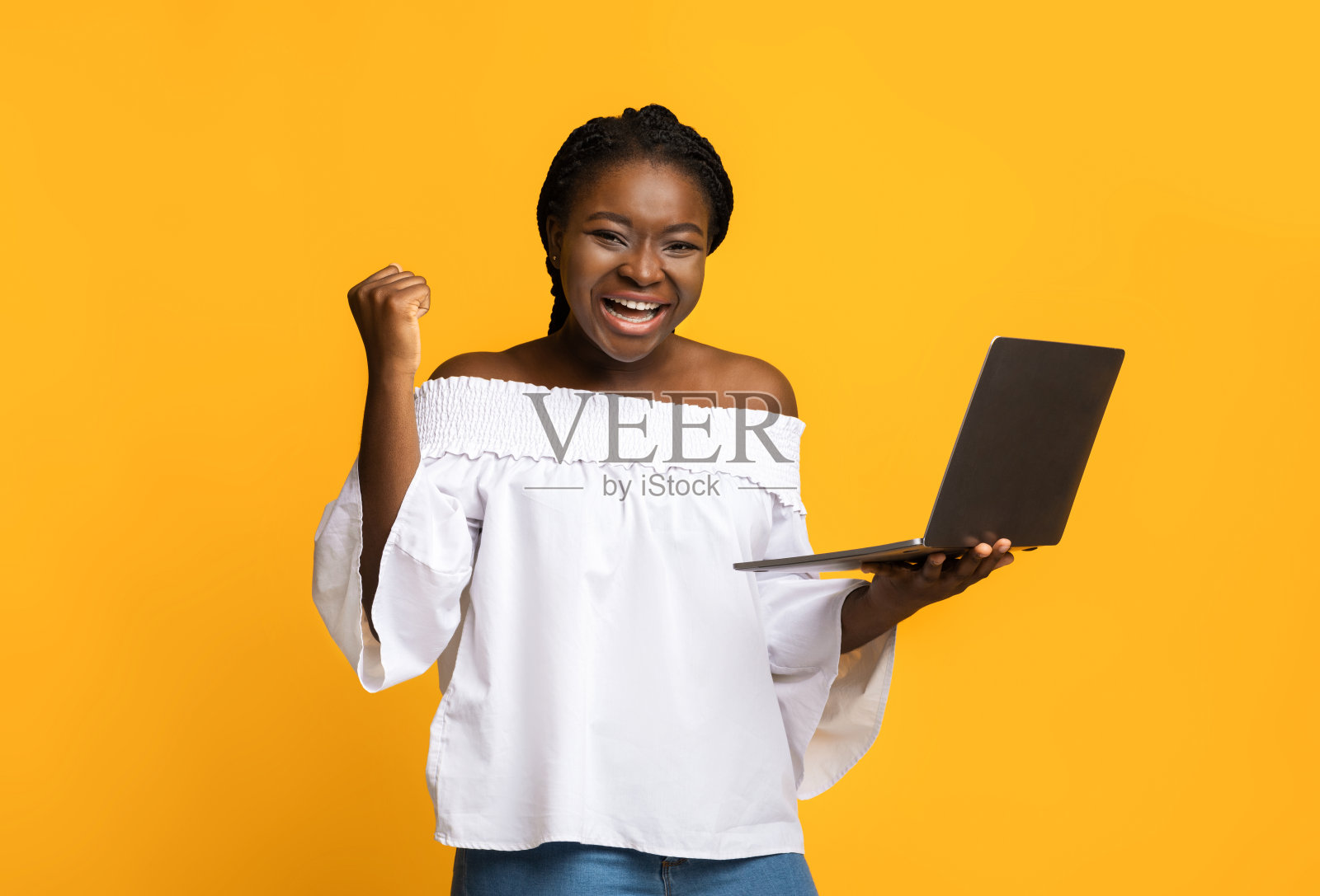 是的。兴奋的非裔美国女士用手提电脑庆祝成功，挥舞着拳头照片摄影图片