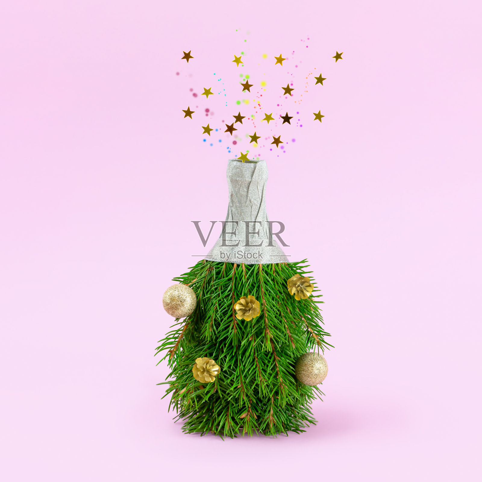 粉红色背景上的香槟酒瓶做成的圣诞树。瓶子爆炸，金色的星星和五颜六色的泡泡。圣诞节和新年的最小概念照片摄影图片
