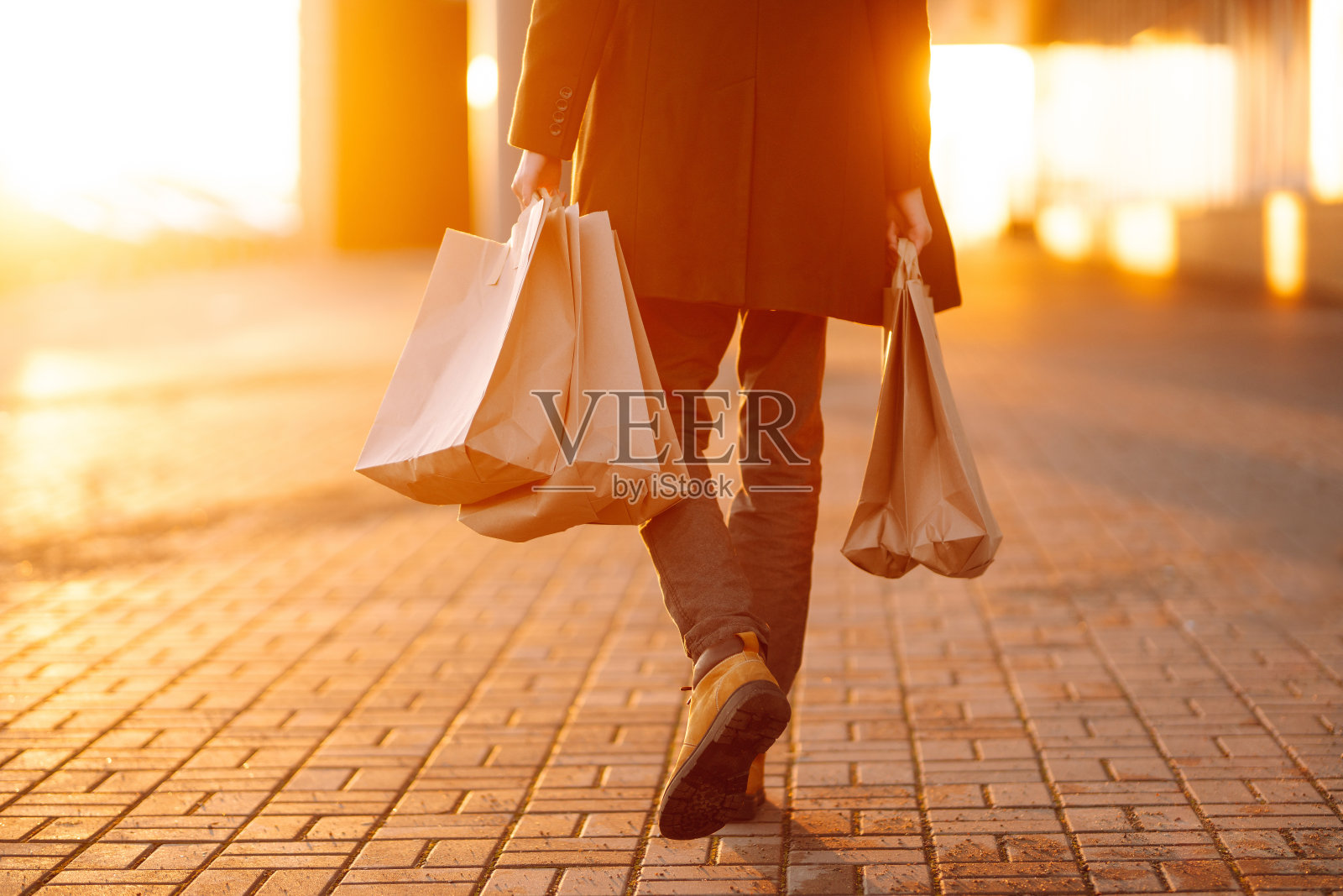 一个年轻人的手与纸袋与购买在日落。照片摄影图片