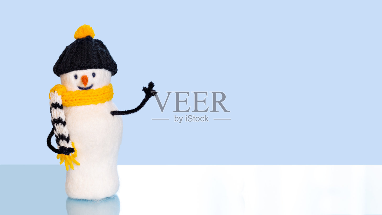 圣诞玩具雪人在一个黑色和黄色的帽子和围巾在蓝色的背景与文字的地方照片摄影图片