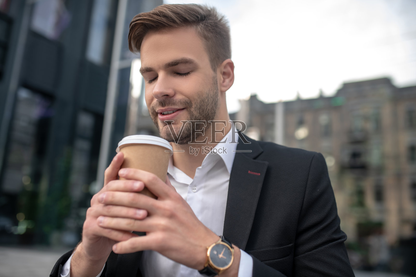 优雅的男性商人闻着咖啡，看起来很放松照片摄影图片
