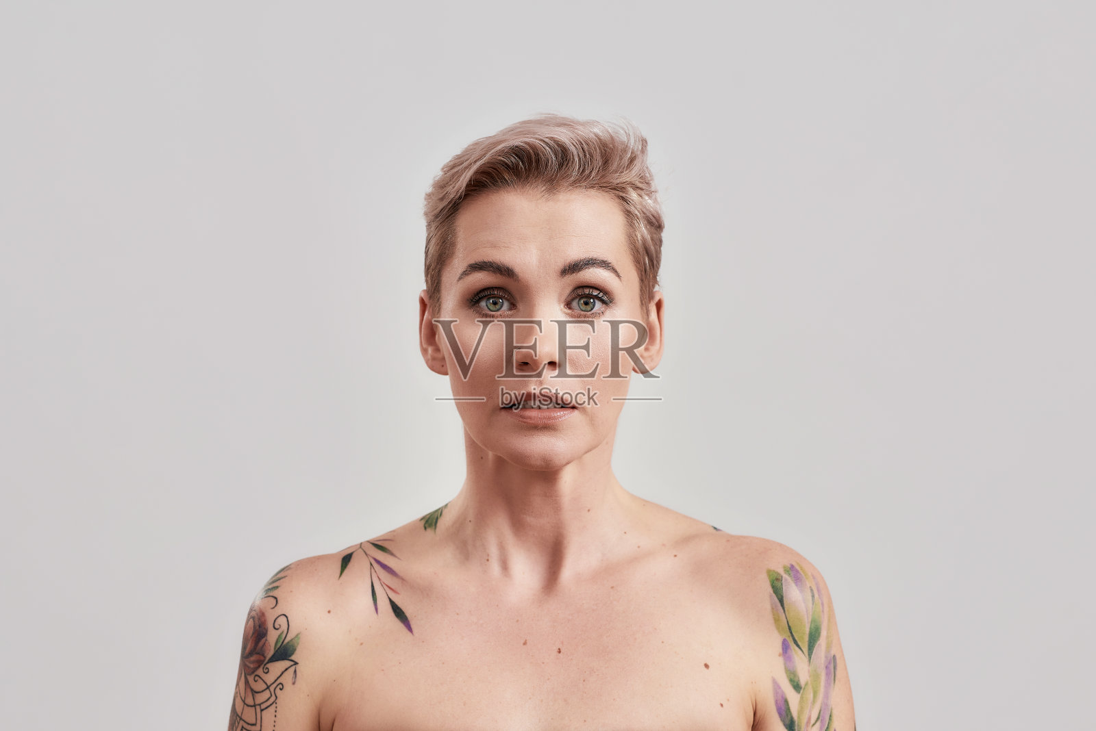 哦。肖像的半裸纹身的女人短发感觉尴尬，傻孤立的光背景照片摄影图片