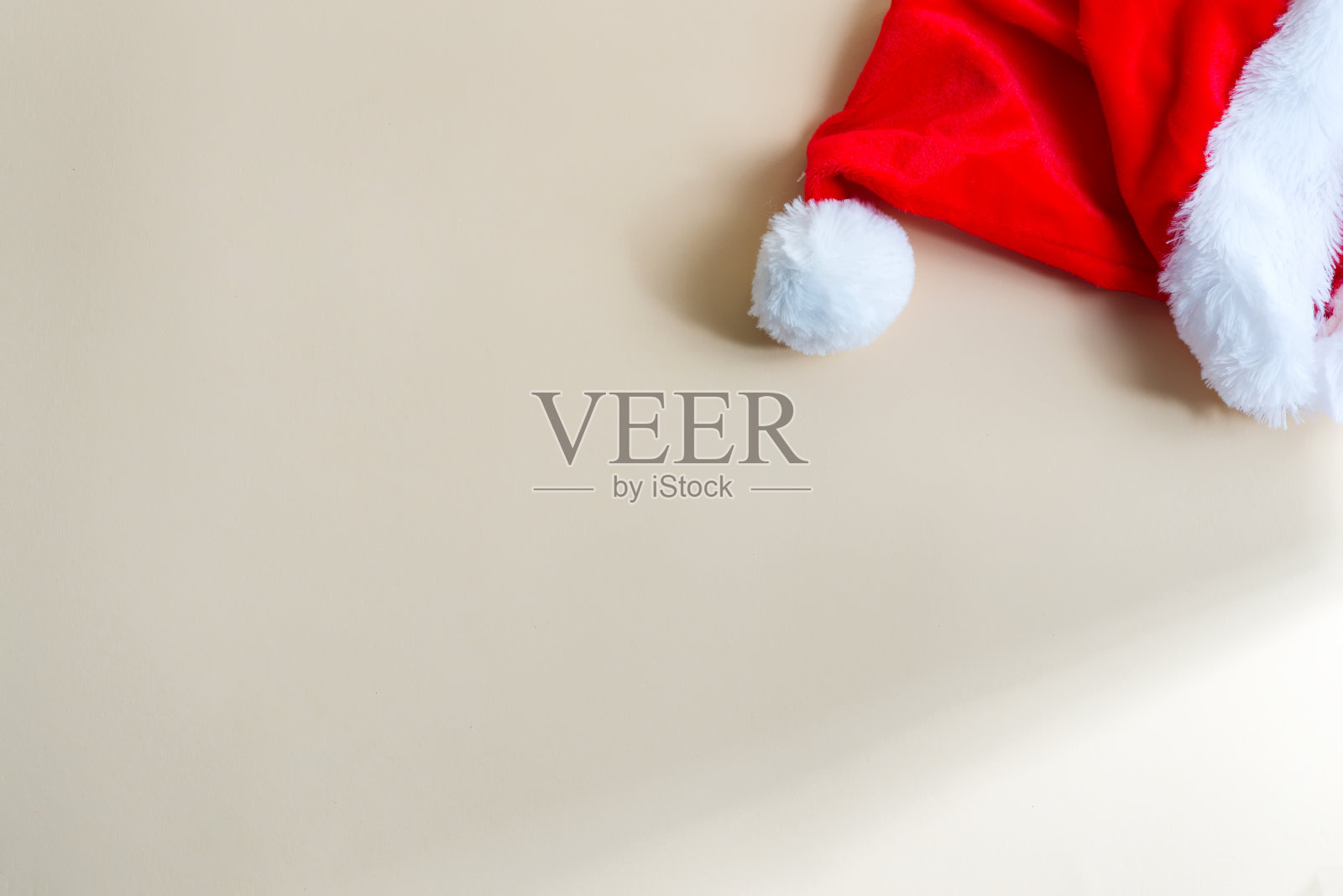 浅米色背景上的红色圣诞老人帽。照片摄影图片