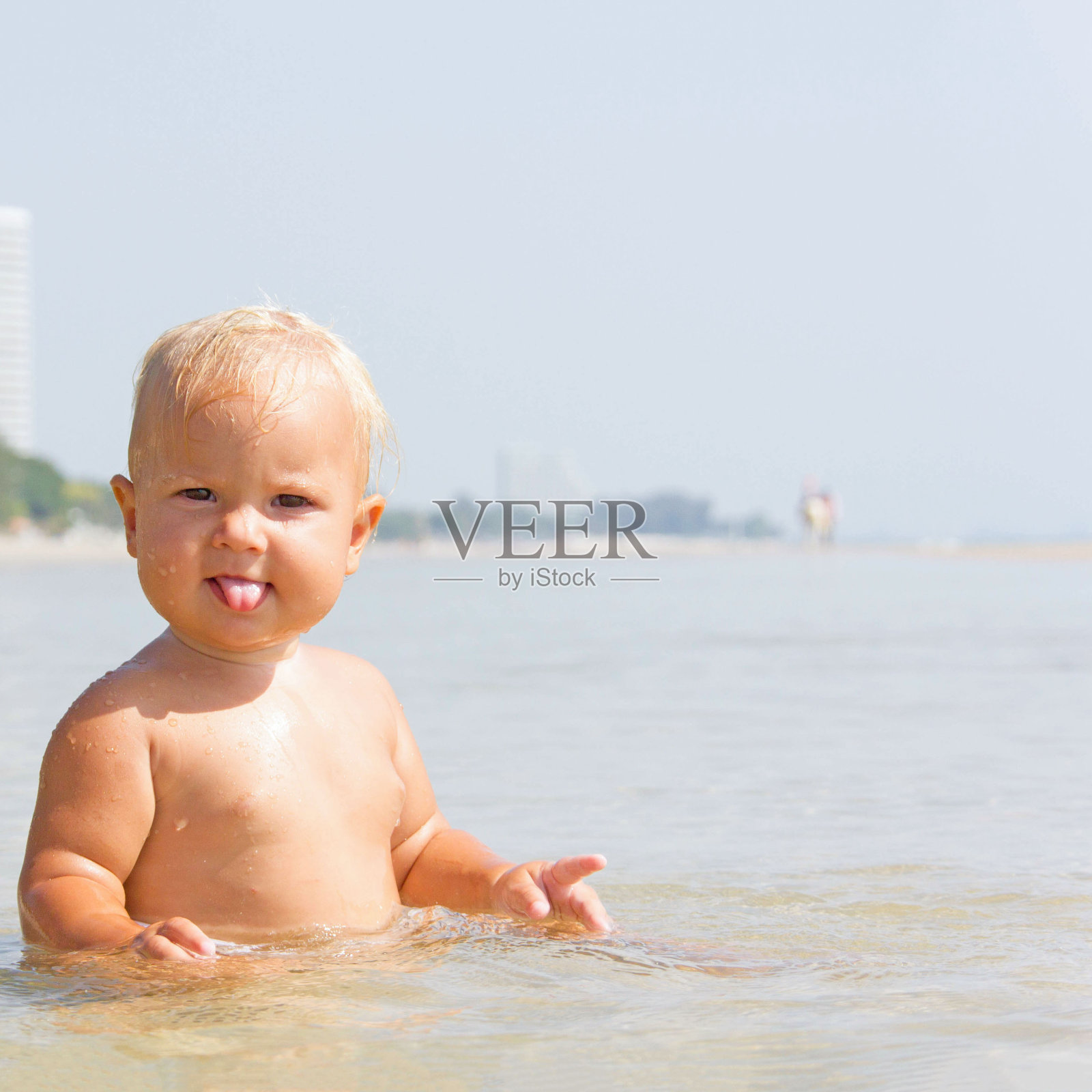 在阳光明媚的夏天，婴儿在海边玩水照片摄影图片