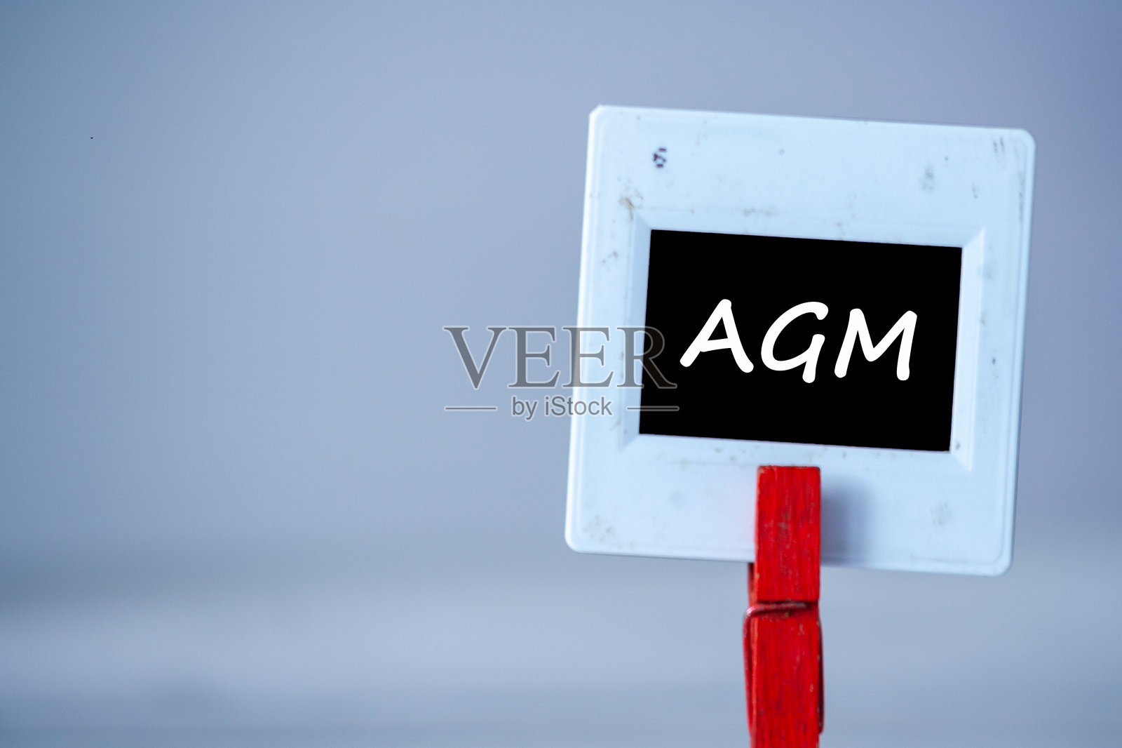 桌子上有一个塑料框架，上面有衣服别针。白色框架与黑色背景和铭文AGM照片摄影图片