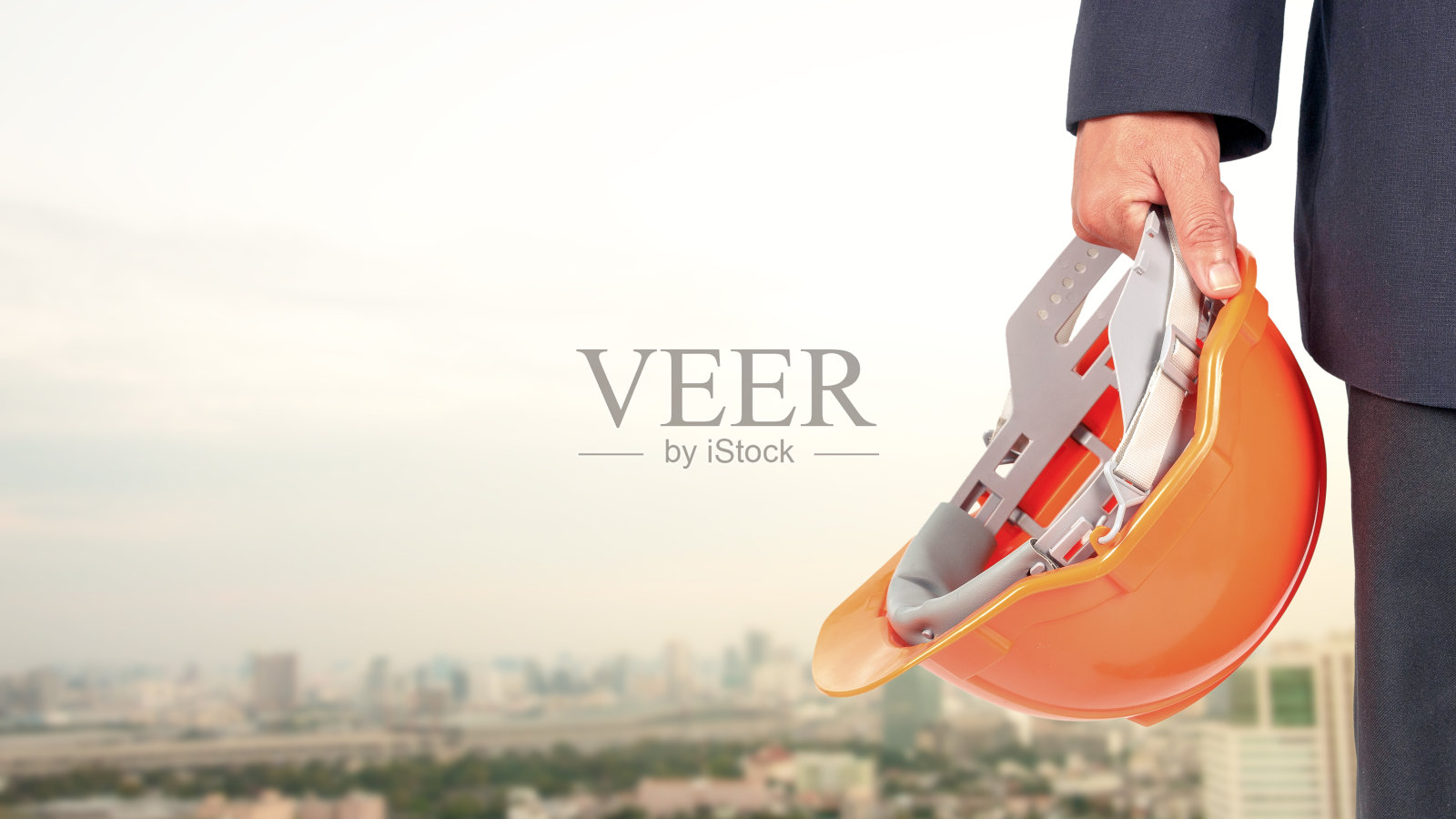 工程师或建筑师在城市高楼的背景上戴着安全帽。照片摄影图片