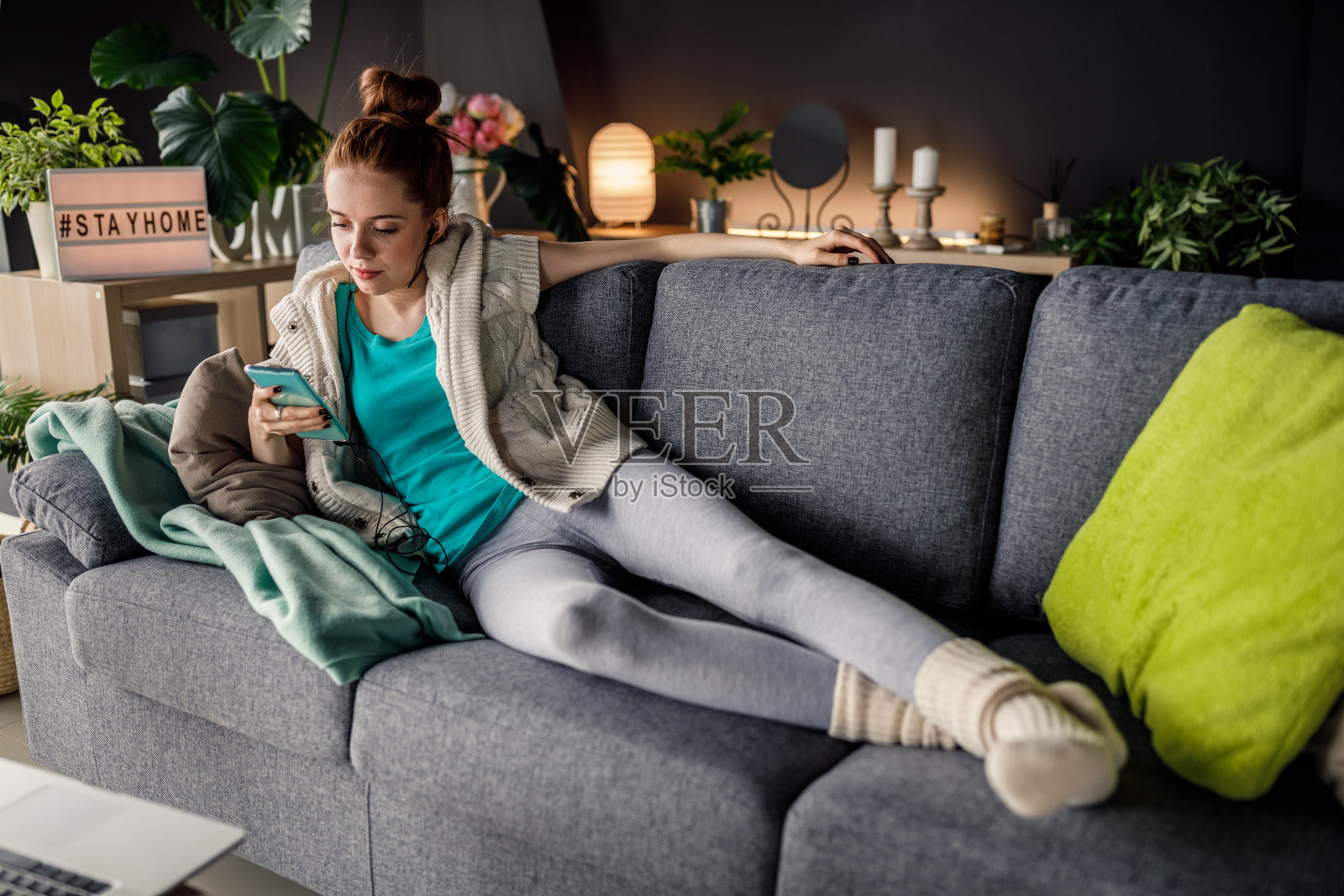 年轻女子在沙发上放松，听着音乐，用着手机照片摄影图片