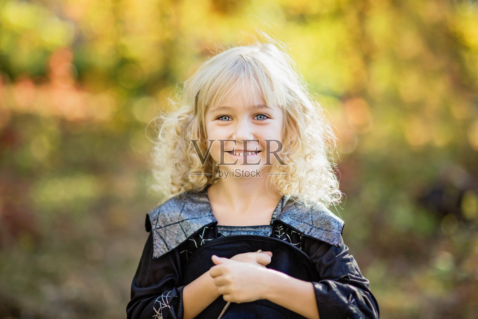 穿着女巫服装的小女孩在户外庆祝万圣节，玩得很开心。照片摄影图片