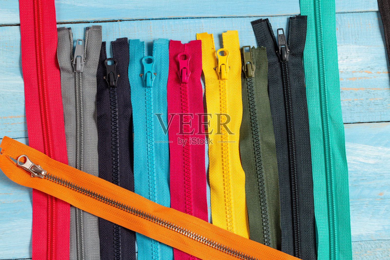 包许多彩色塑料拉链条纹与滑块图案手工缝制裁剪在蓝色牛仔布背景近距离选择性焦点照片摄影图片