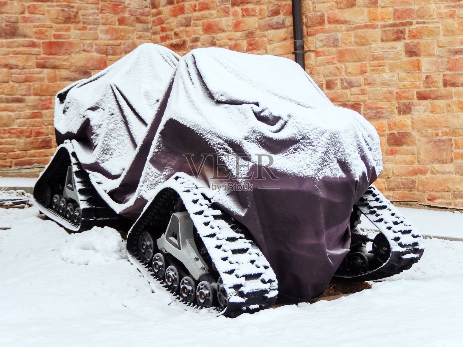 一辆带斗篷的履带四轮摩托车停在石墙附近照片摄影图片