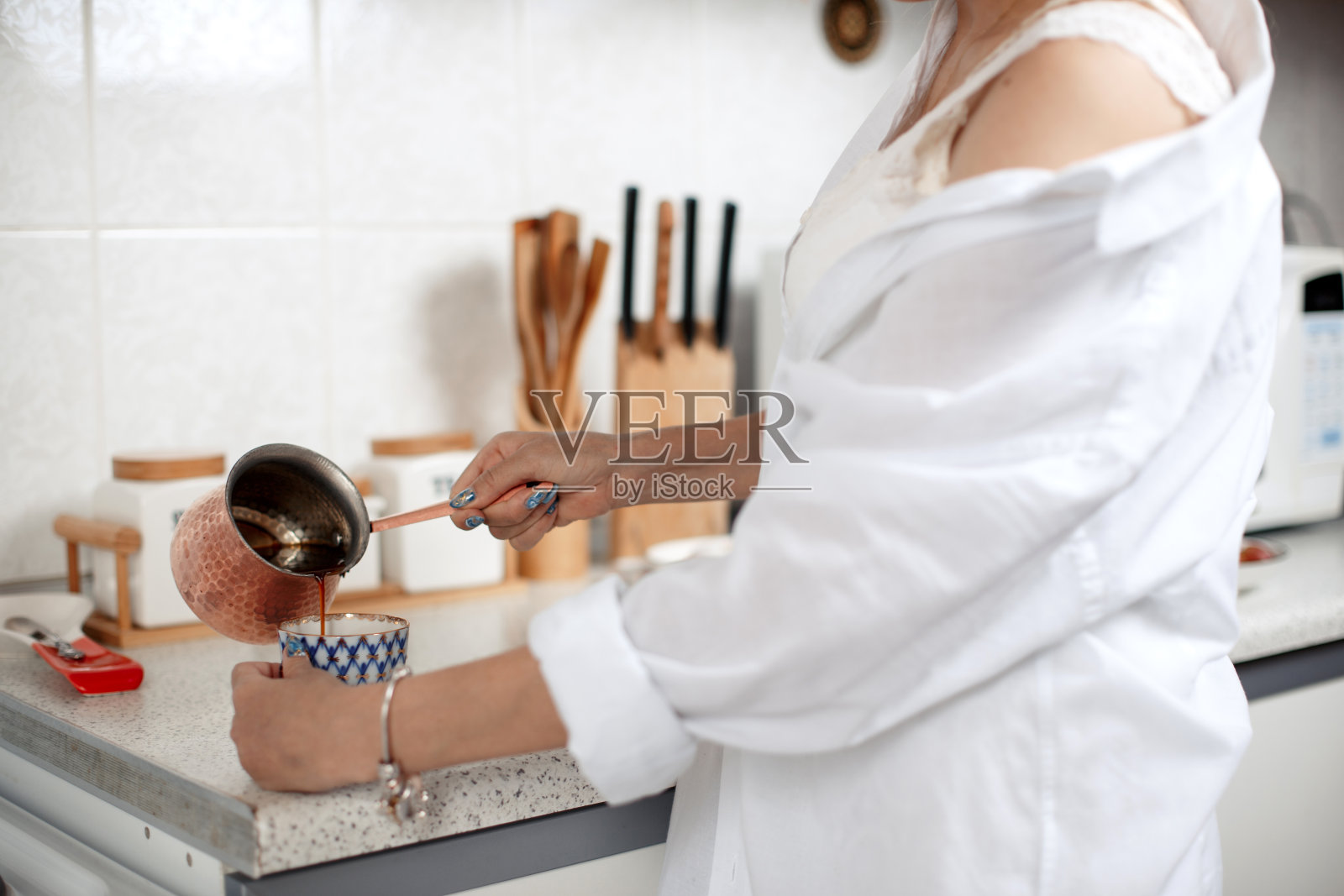 年轻美丽的亚洲女孩米色蕾丝短裤，白衬衫准备早上的咖啡。有选择性的重点。小的关注领域。照片摄影图片