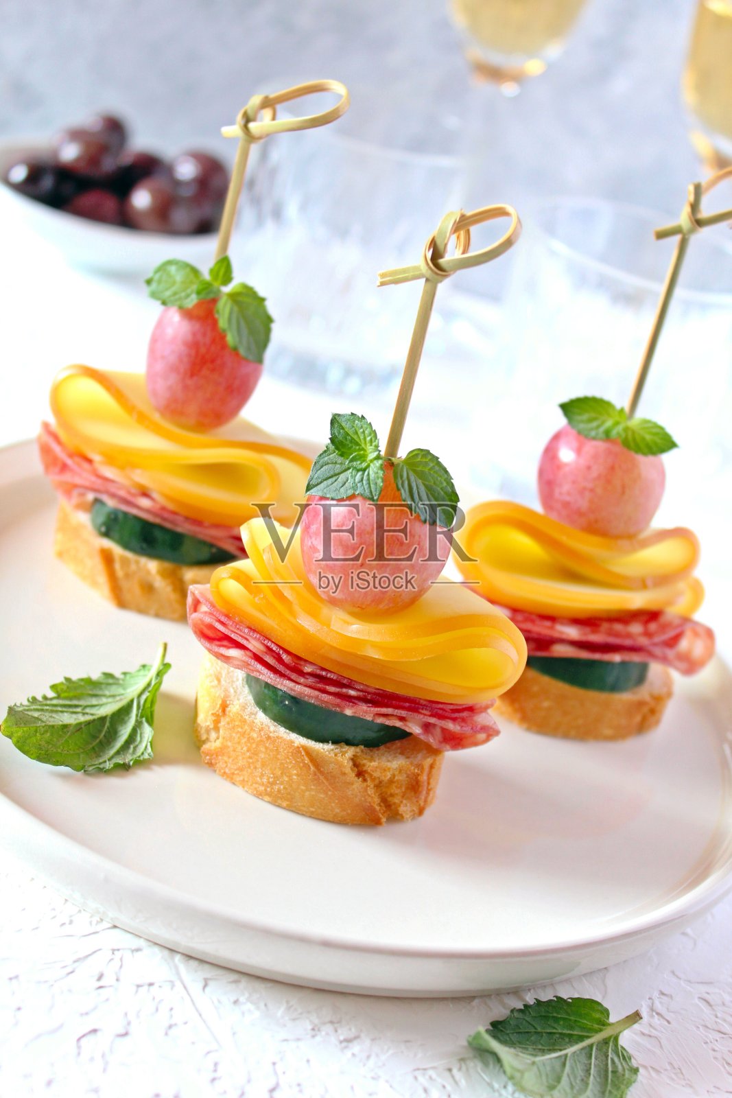 搭配黄瓜、意大利腊肠、奶酪、葡萄和白葡萄酒的美味小吃。照片摄影图片