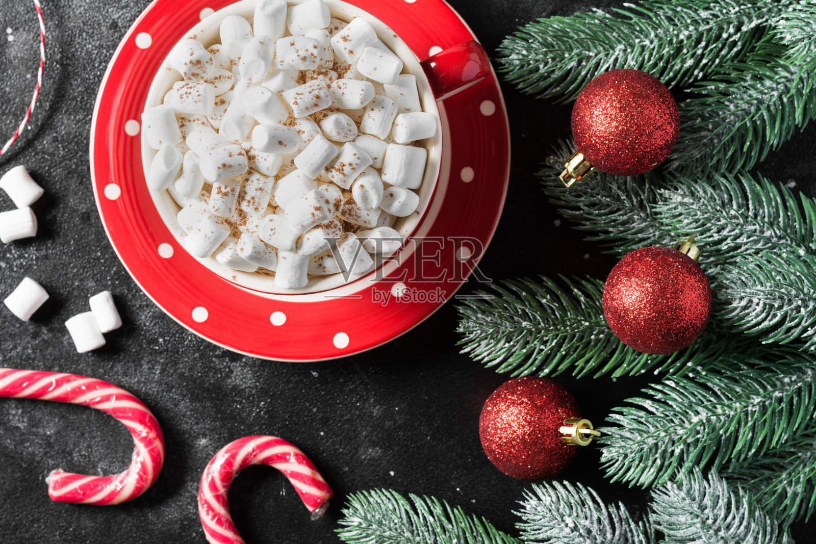 红色的杯子里放着可可和棉花糖，黑色的桌子上装饰着圣诞节。用红色组成。圣诞贺卡的概念。顶部视图与复制空间照片摄影图片