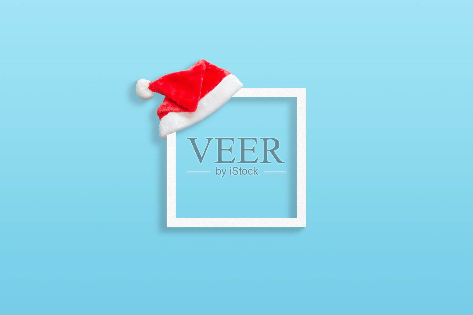 圣诞白色框架与圣诞老人的帽子在蓝色蜡笔表面照片摄影图片