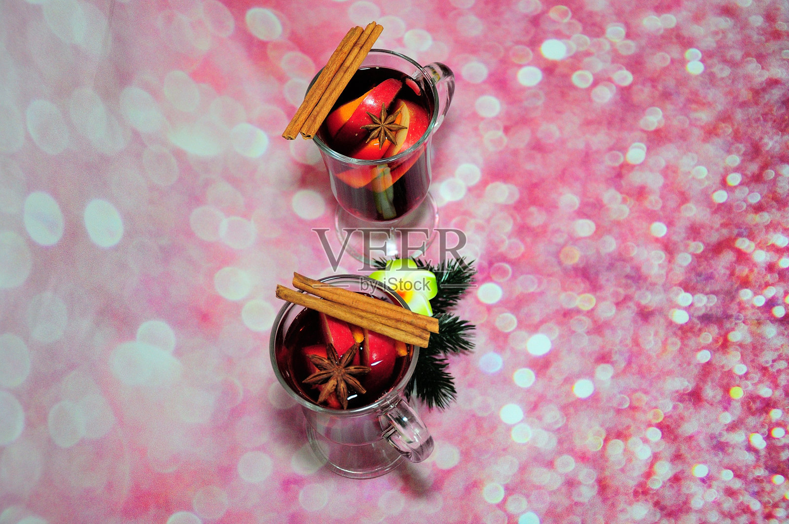 两杯热红酒配上肉桂和茴芹，背景是粉红色的闪闪发光。照片摄影图片