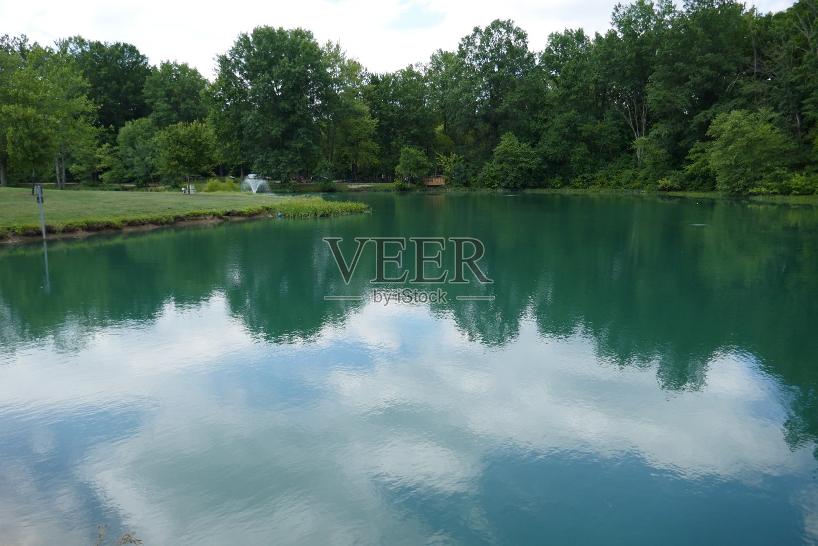 田园诗般的湖景与森林树木和云景倒映在水中照片摄影图片