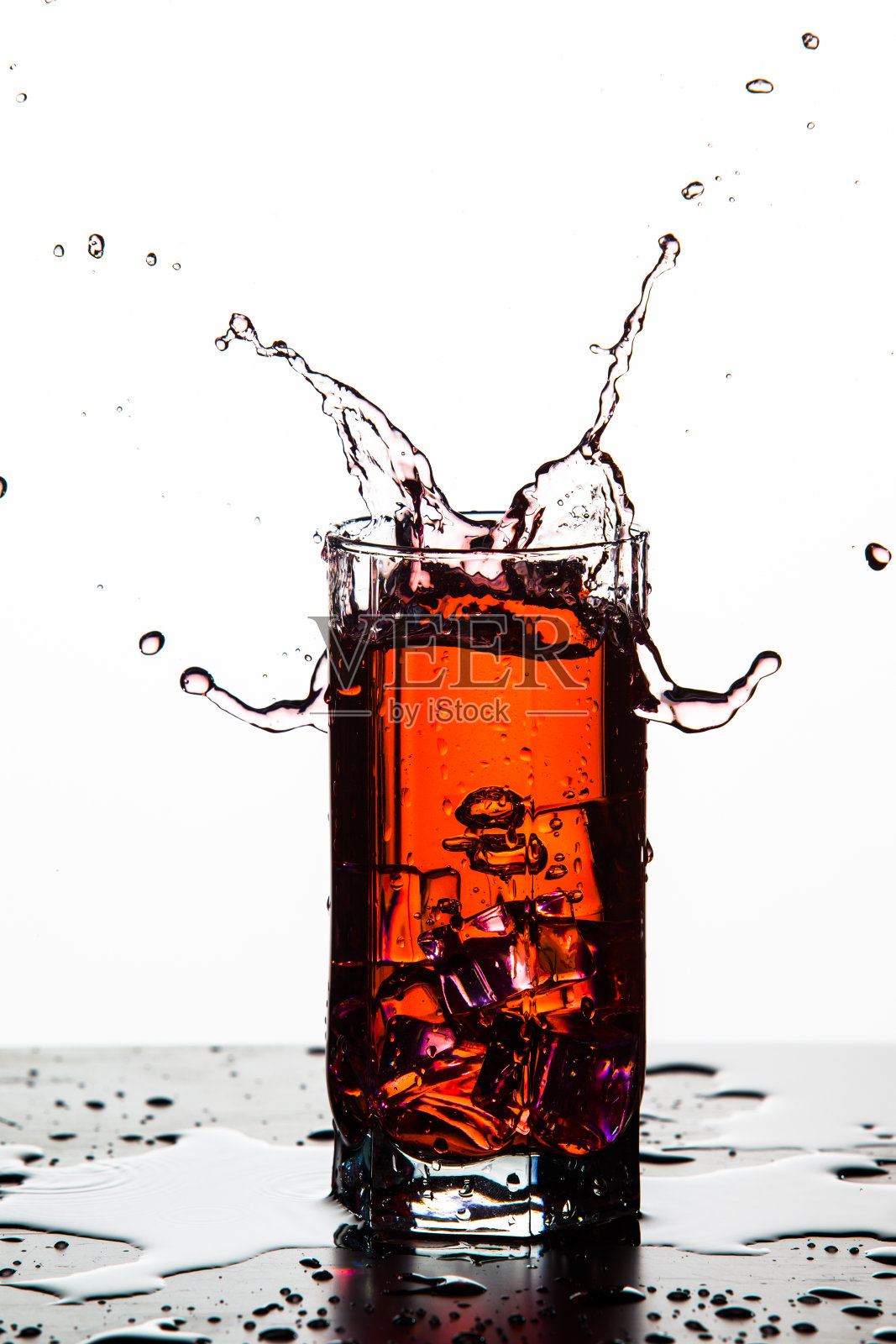 摄影。彩色液滴与冰块落在高脚杯。在白色的背景下。垂直的图像照片摄影图片