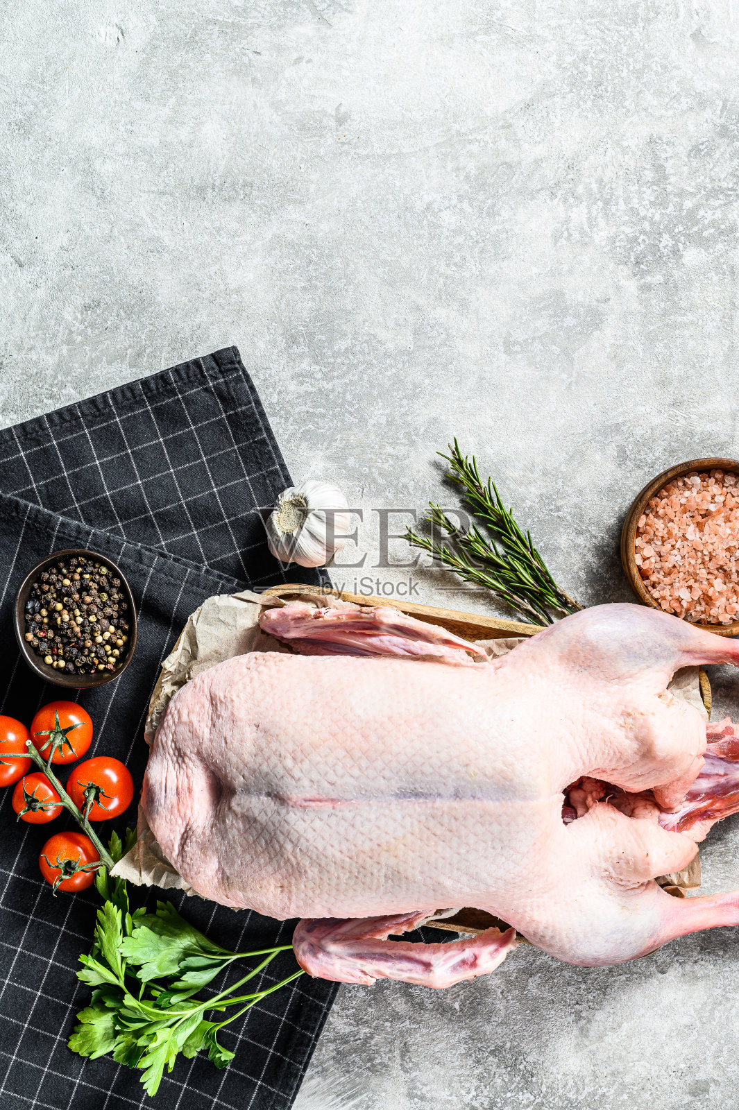 整个生鸭。用粉盐，大蒜，欧芹和迷迭香烹饪。灰色的背景。前视图。空间的文本照片摄影图片