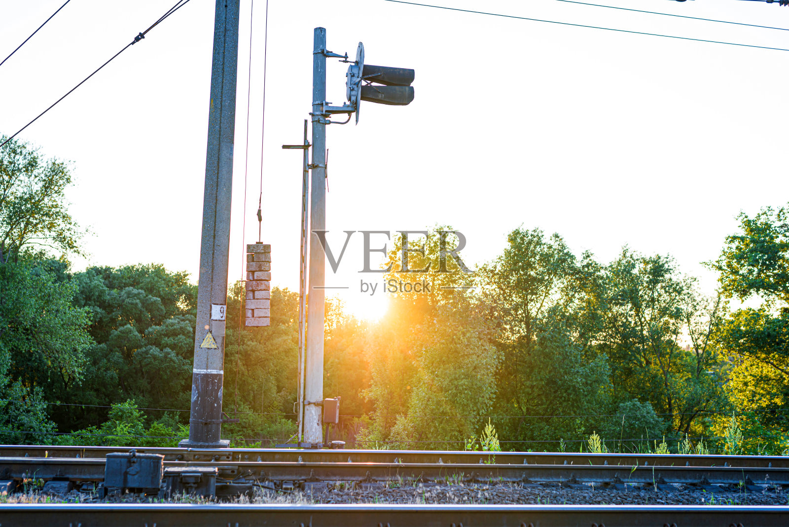 绿树和夕阳映衬下的铁路交通灯照片摄影图片