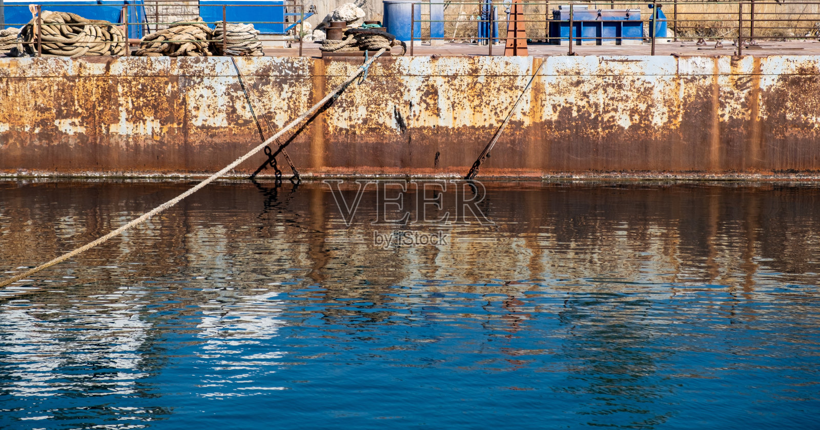 系在甲板上的钢系柱上的系缆。旧工业港口码头照片摄影图片