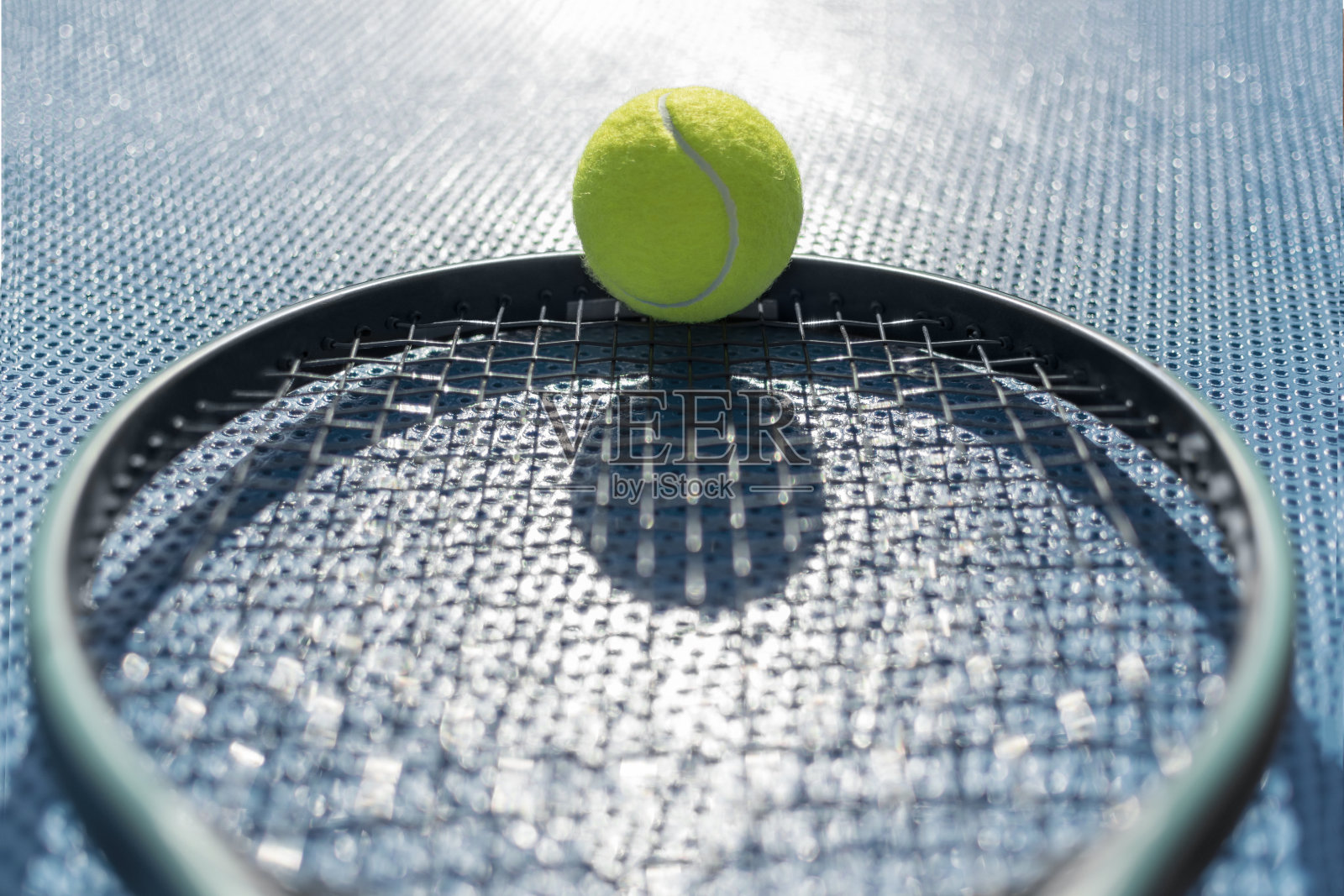 网球比赛运动概念：逆光下蓝色背景的网球拍上的网球，选择性聚焦，带阴影照片摄影图片