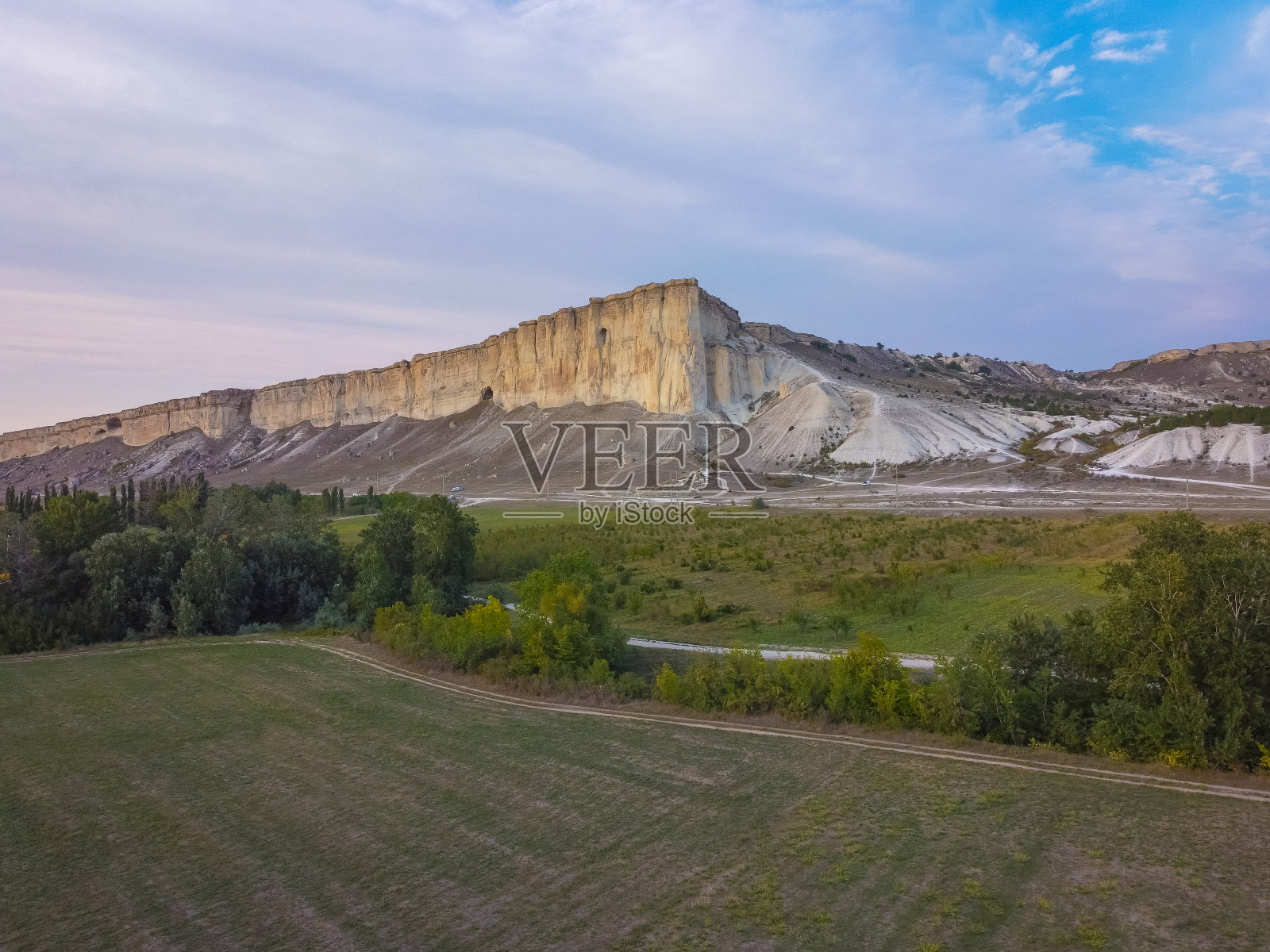克里米亚的白岩。克里米亚风光。高岩石落基山。白色的岩石映衬着美丽的日落，轻云飞过岩石和通往岩石脚下的道路。照片摄影图片
