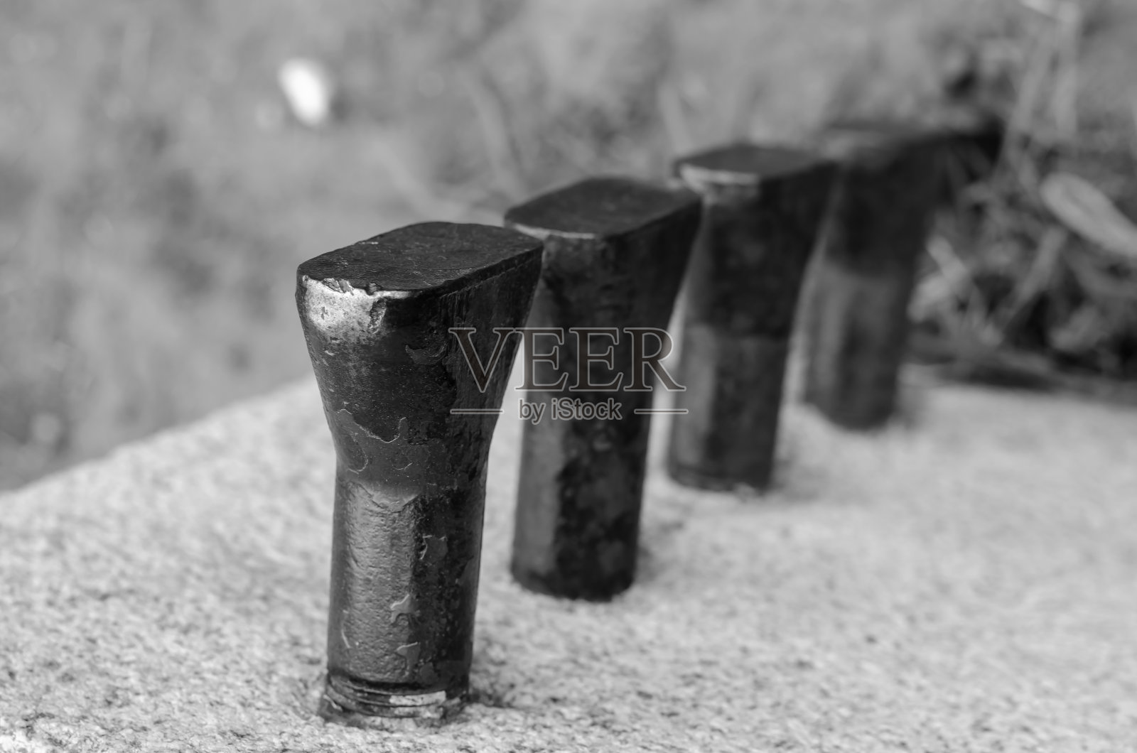 一排用石头包裹的金属锚。照片摄影图片