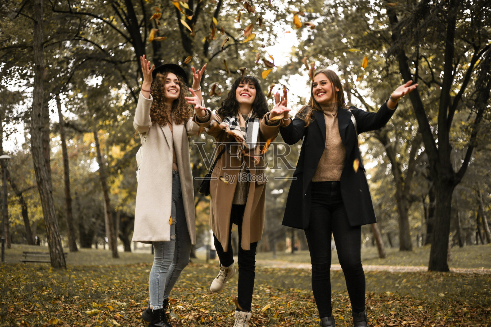 幸福的女人在秋天的公园里，一滴一滴的落叶照片摄影图片