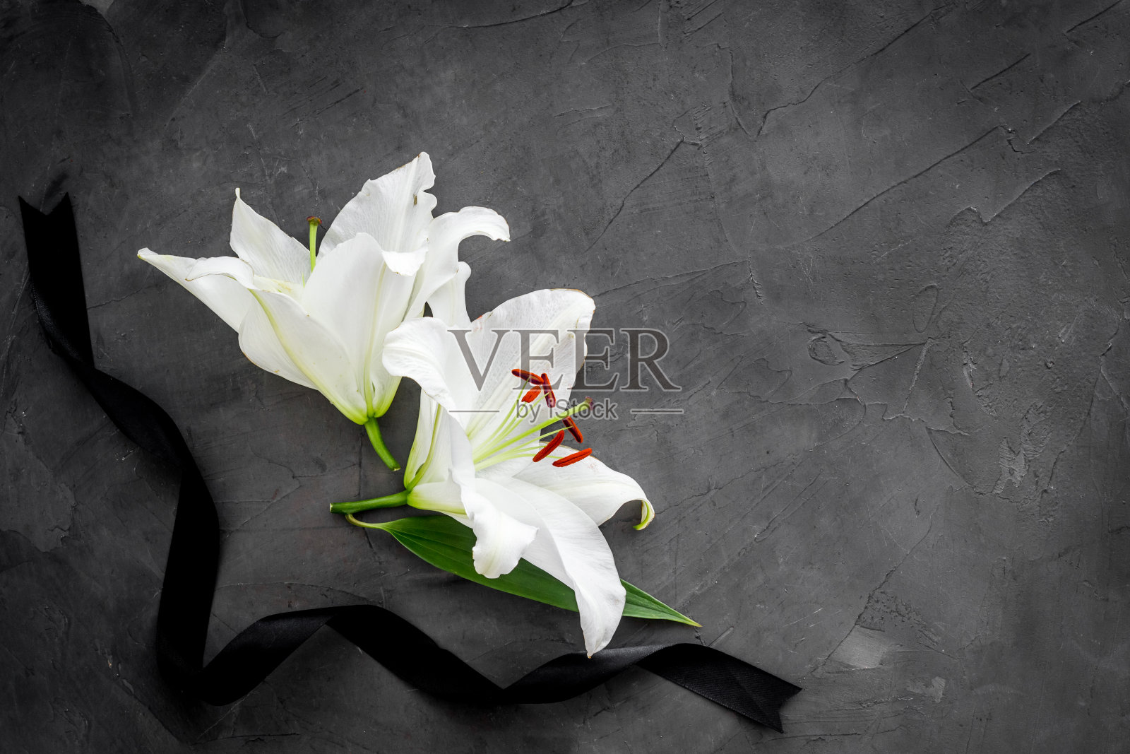 平铺的百合花和黑丝带。葬礼的象征照片摄影图片