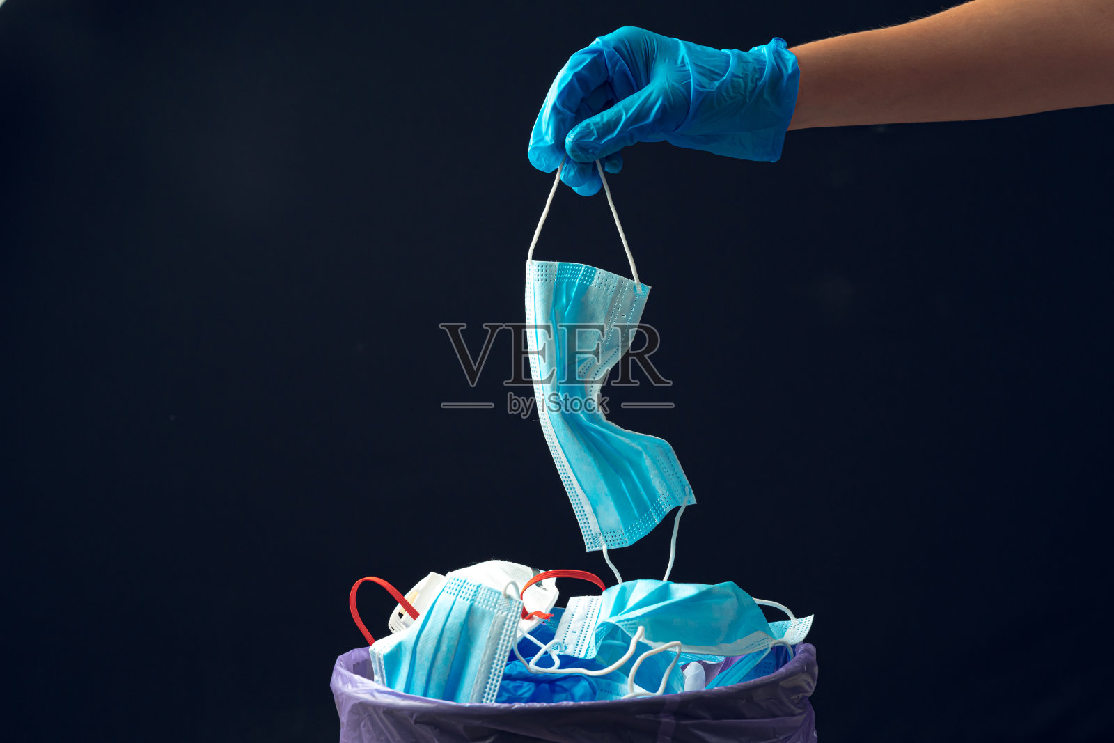 用手把用过的脏口罩放在垃圾桶里。照片摄影图片