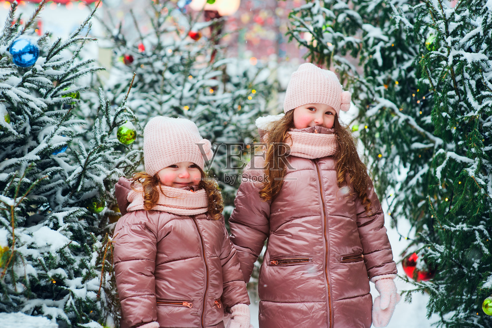 圣诞肖像两个快乐的姐妹在户外玩在冬天的雪城装饰新年假期。孩子们在户外度过圣诞假期和旅行照片摄影图片