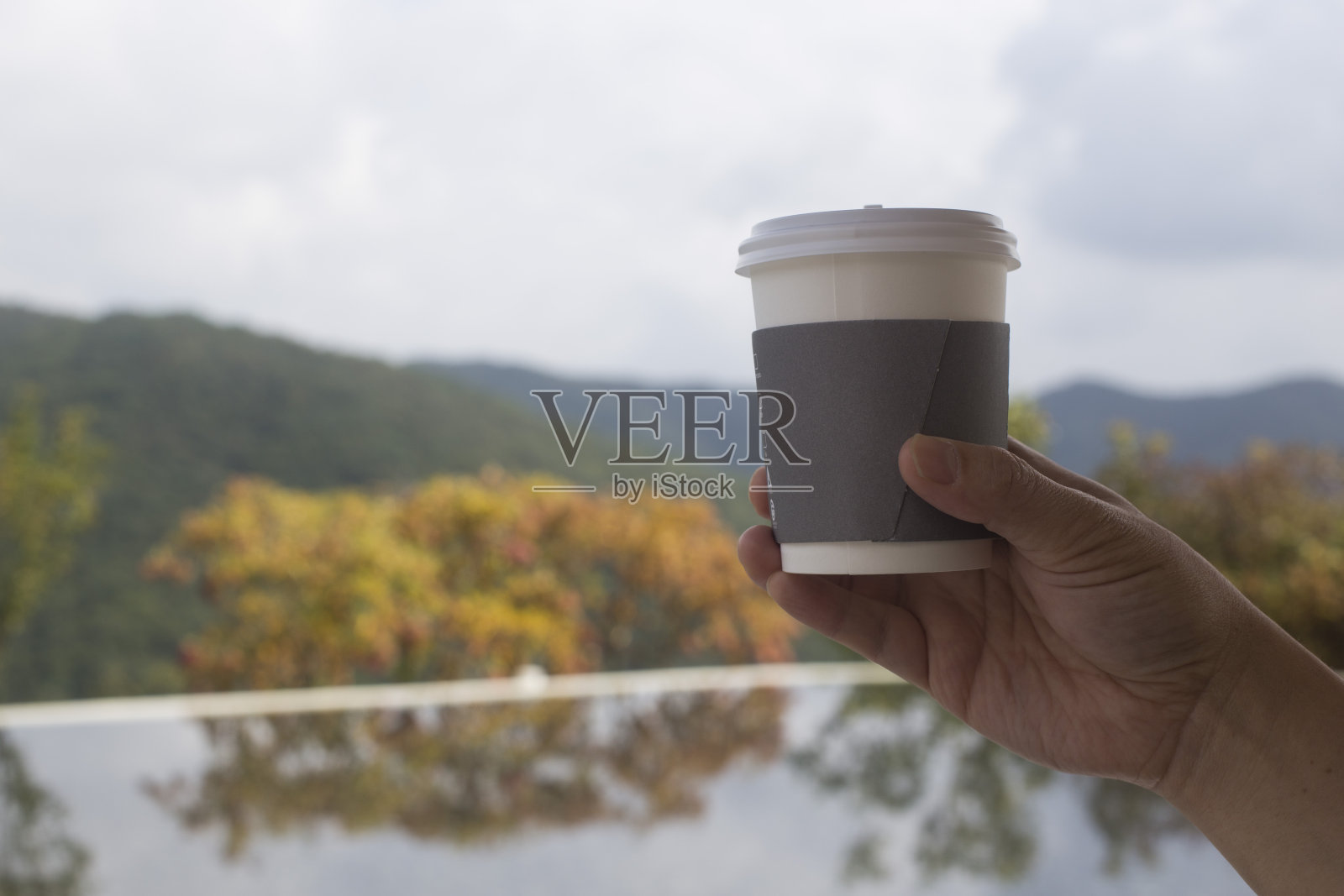 男人手握咖啡纸杯在山景背景。照片摄影图片