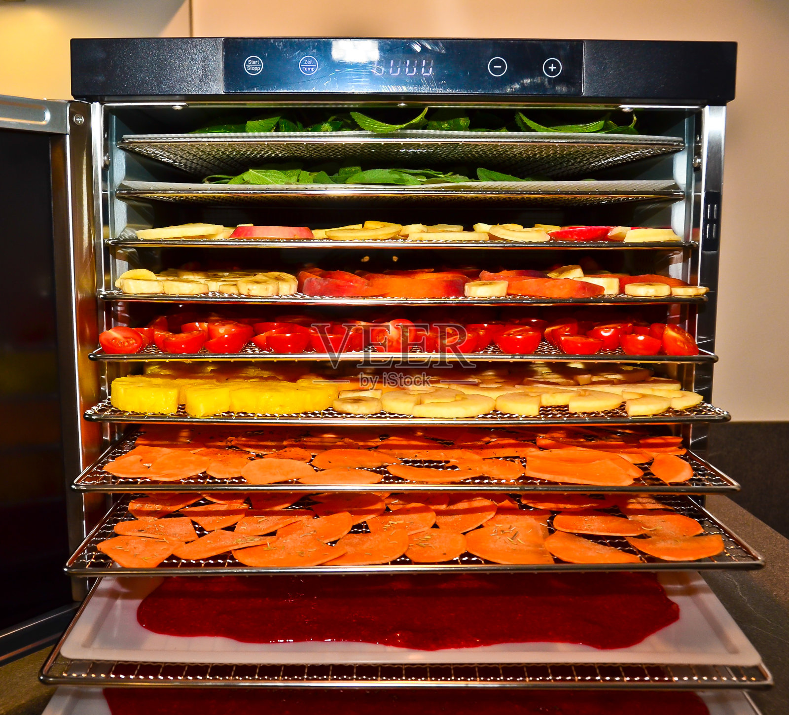 一个盘子烘干机，一个装满不同水果和蔬菜的干燥窑，随时准备开始照片摄影图片