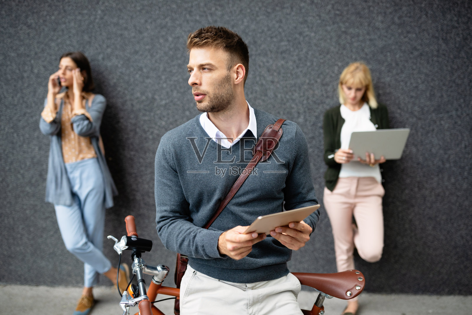 一群手持不同数码设备的年轻商务人士照片摄影图片