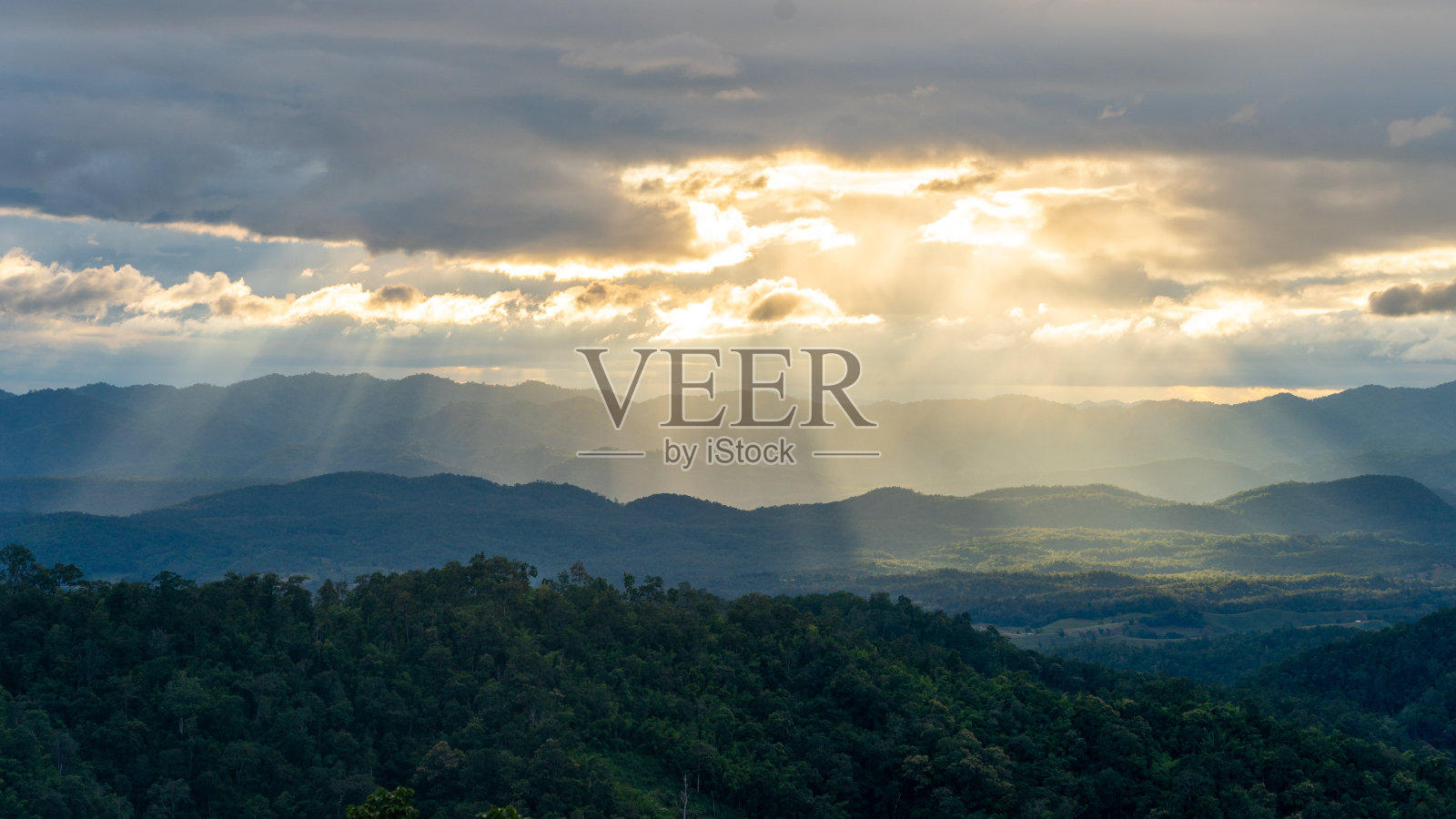 泰国德，金色的阳光透过多云的天空和绵延的山脉照片摄影图片