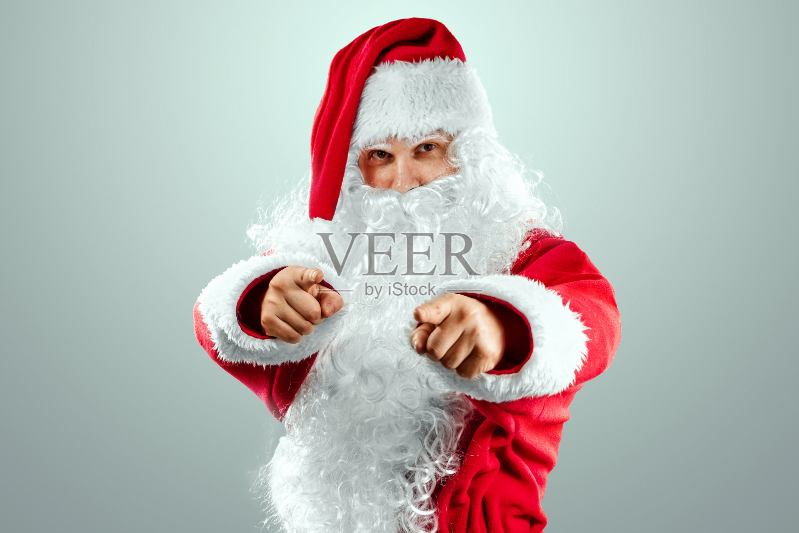 圣诞老人的肖像穿着红色的衣服指向他的手指，灯光背景。概念为平安夜、假期、节日横幅、新年。照片摄影图片