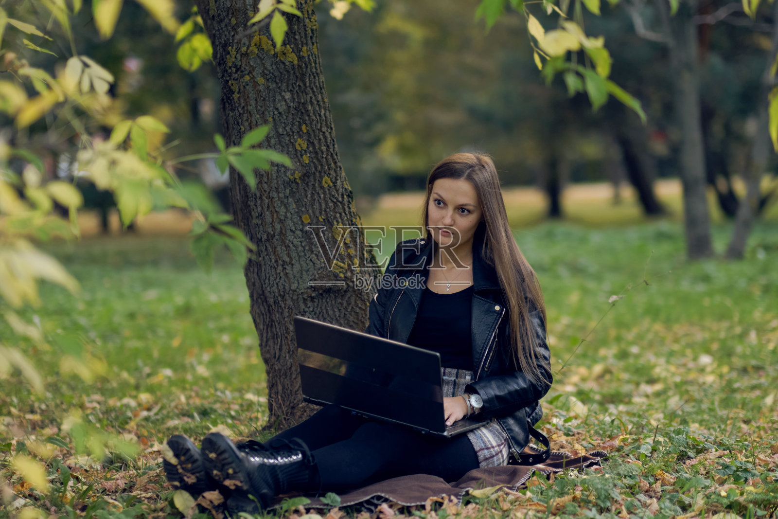 一个年轻女子在公园里为一台笔记本电脑工作。这个学生正在准备考试照片摄影图片