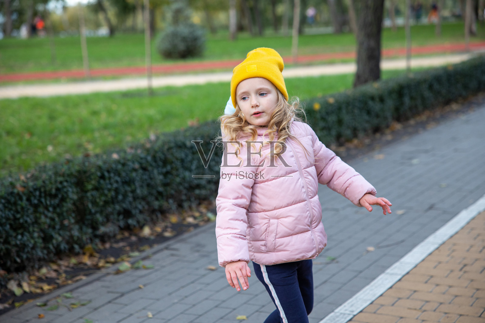 小女孩在公园里散步。照片摄影图片