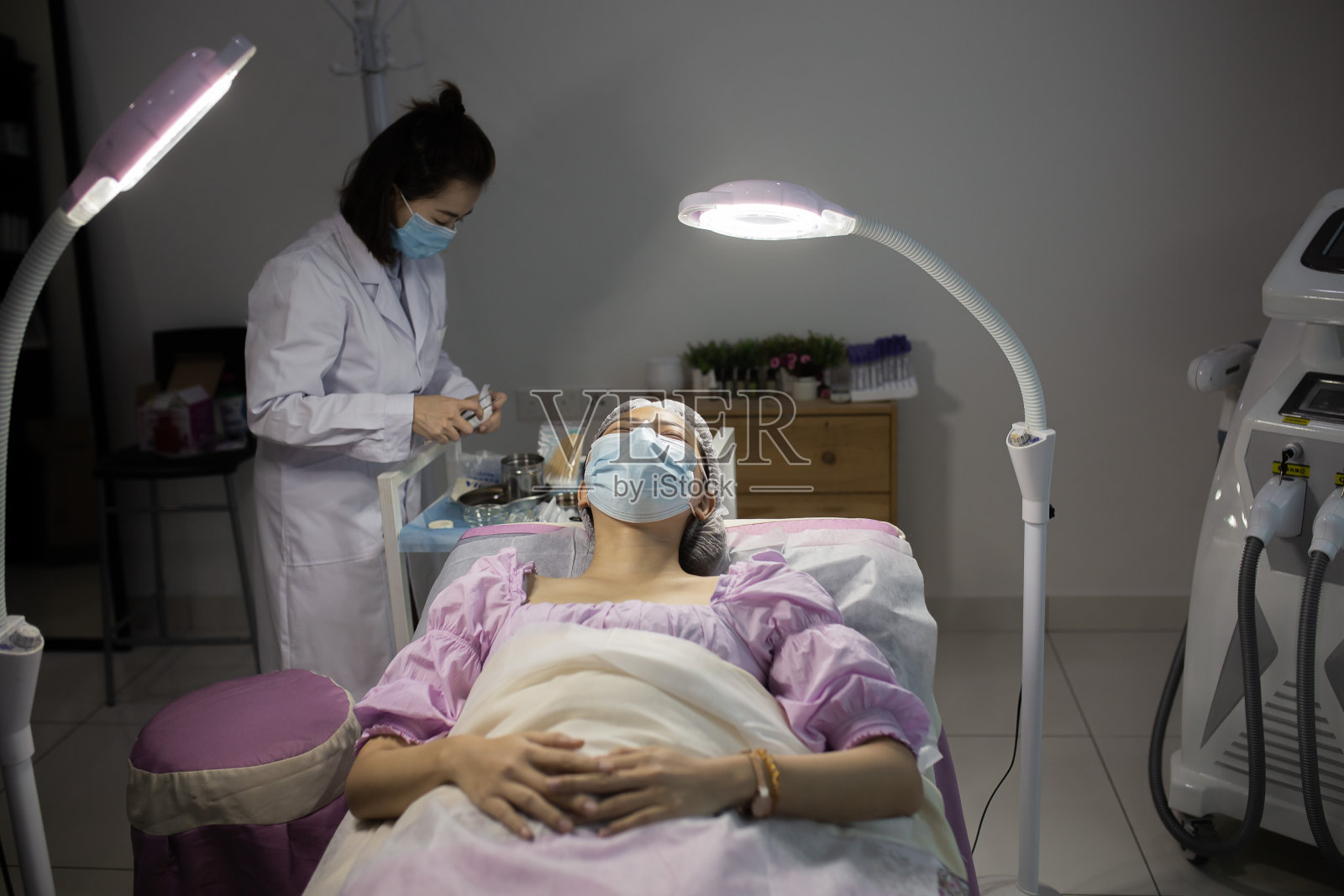 亚洲华人美容师正在客户脸上涂抹保湿霜。女人皮肤的过程。天然的化妆品。面部护理。照片摄影图片