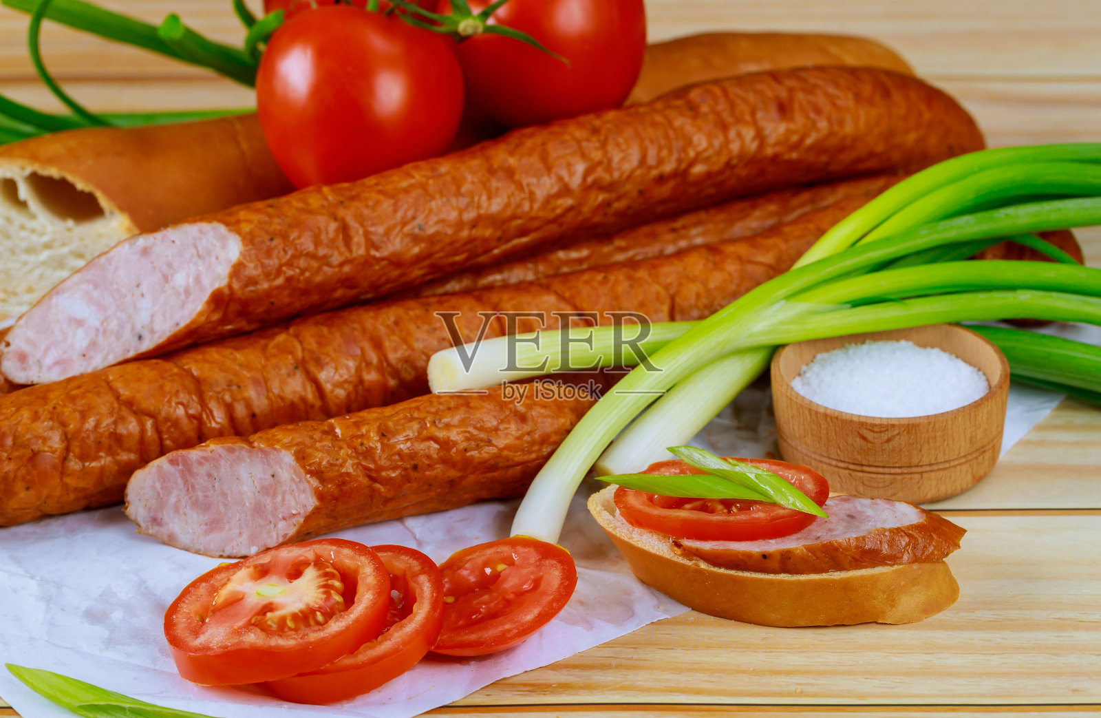 木质背景上放韭菜、番茄和波兰熏肠。照片摄影图片