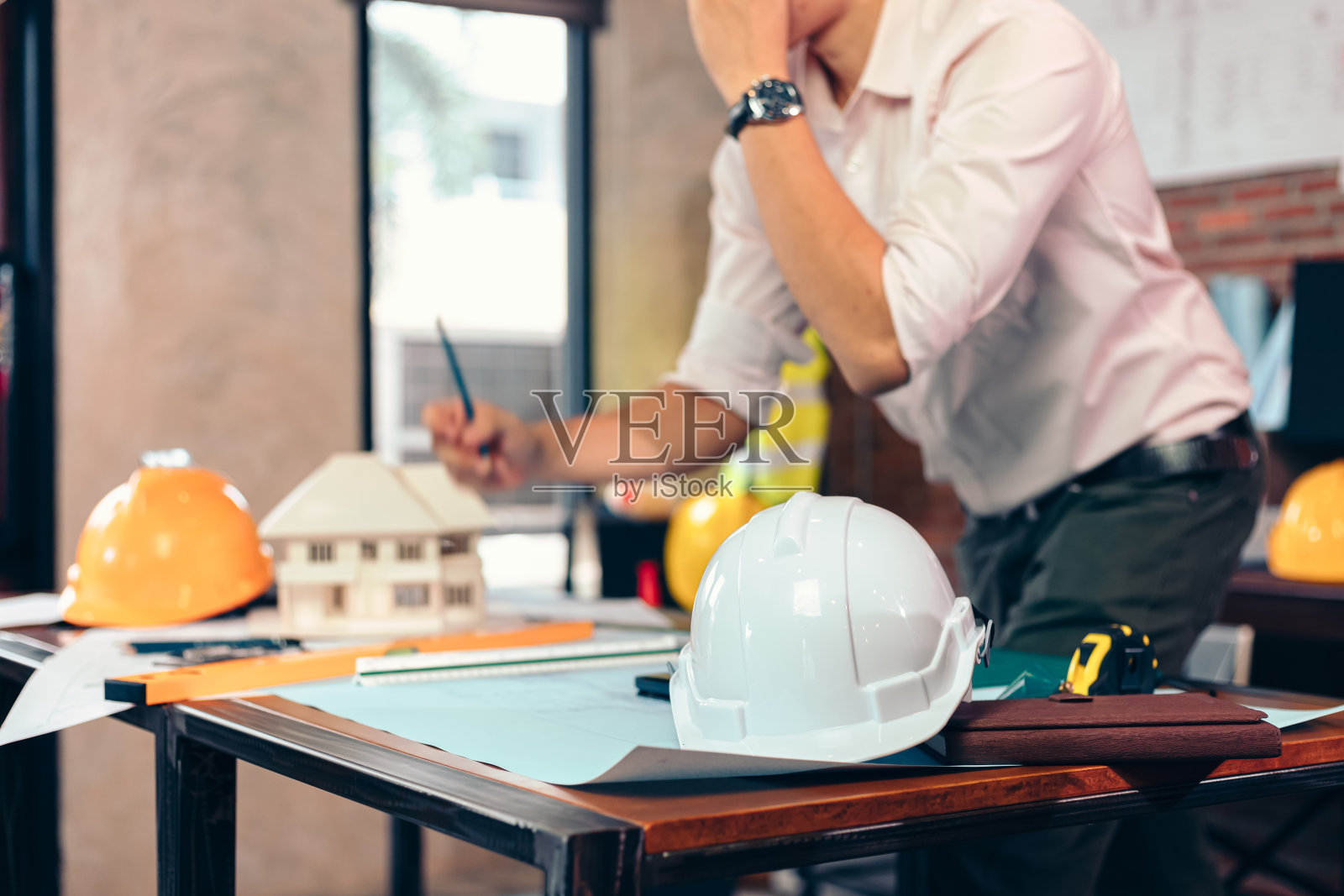 现场施工时将安全帽放在桌子上。建筑师，工程师和商人阅读规划背景。照片摄影图片