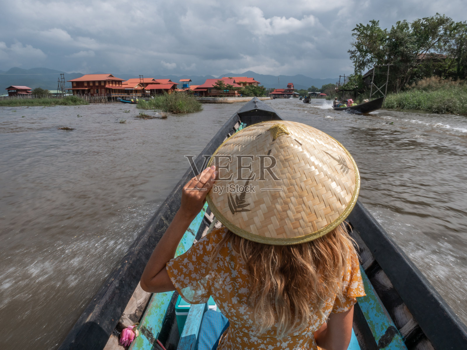 在缅甸茵莱湖上乘坐长尾船的妇女照片摄影图片