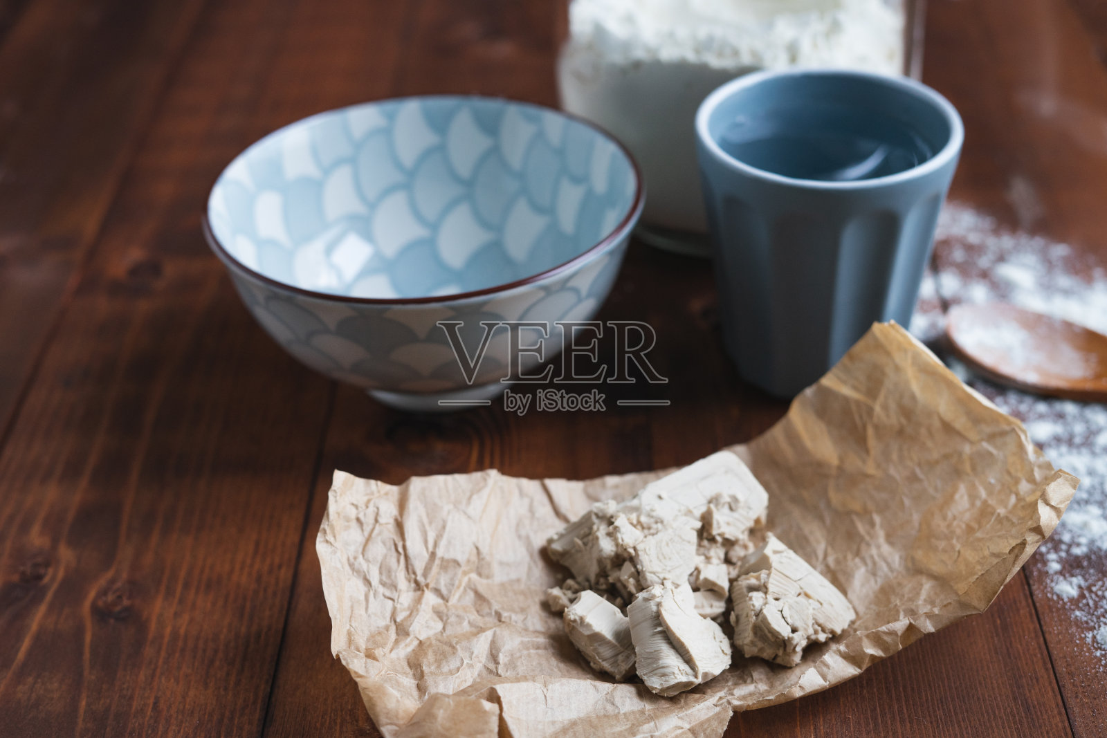 在纸上的酵母，容器和原料在木质底座上制作酸面团。照片摄影图片