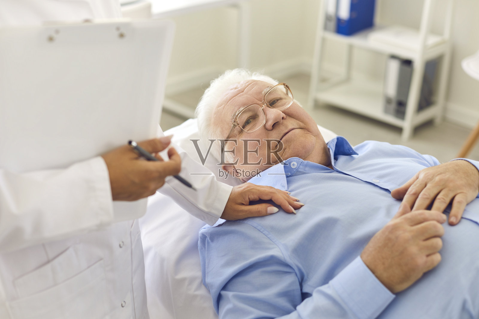 放松的老年男性病人躺在医院办公室的床上体检照片摄影图片