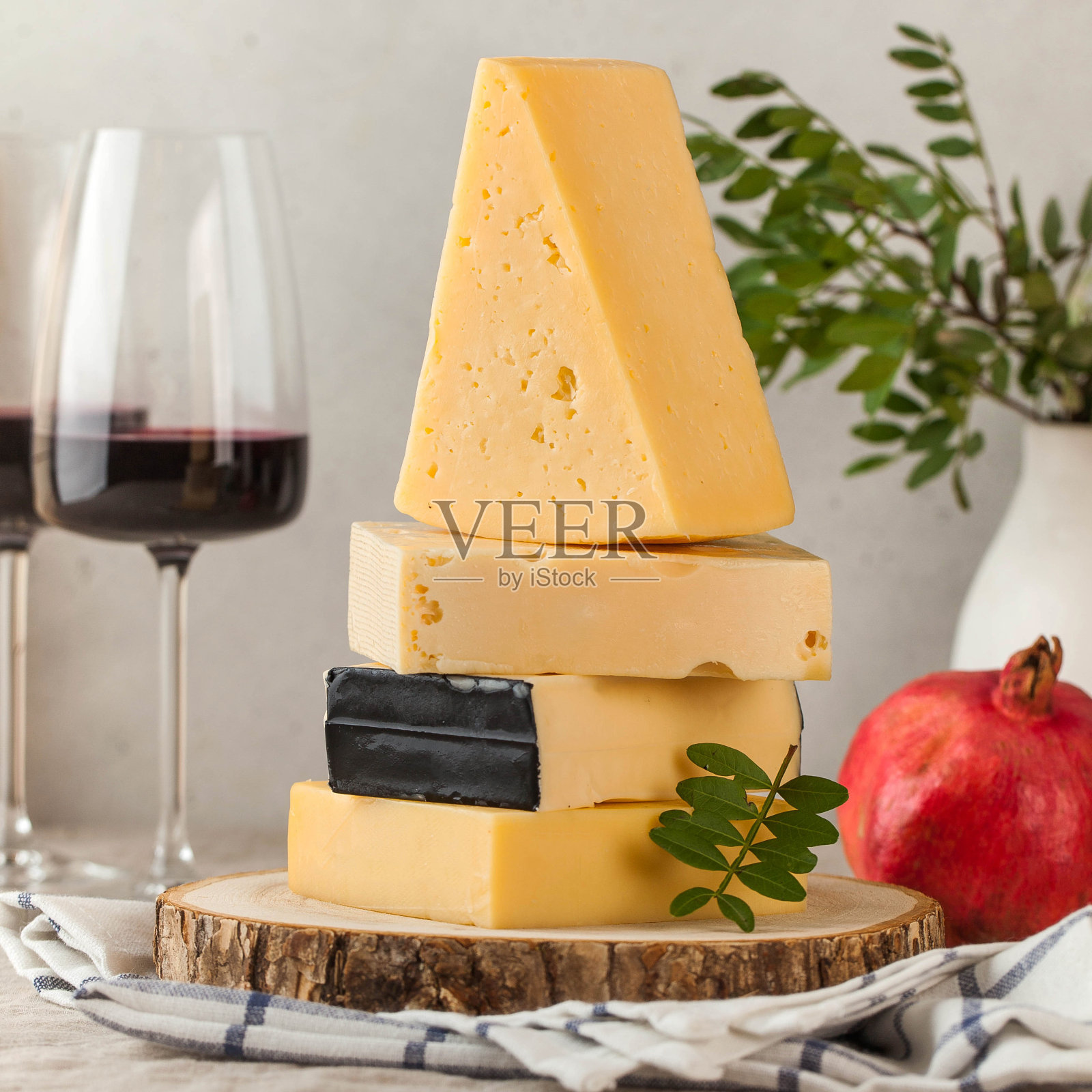 亚麻桌布上放着什锦奶酪、红酒和石榴。照片摄影图片